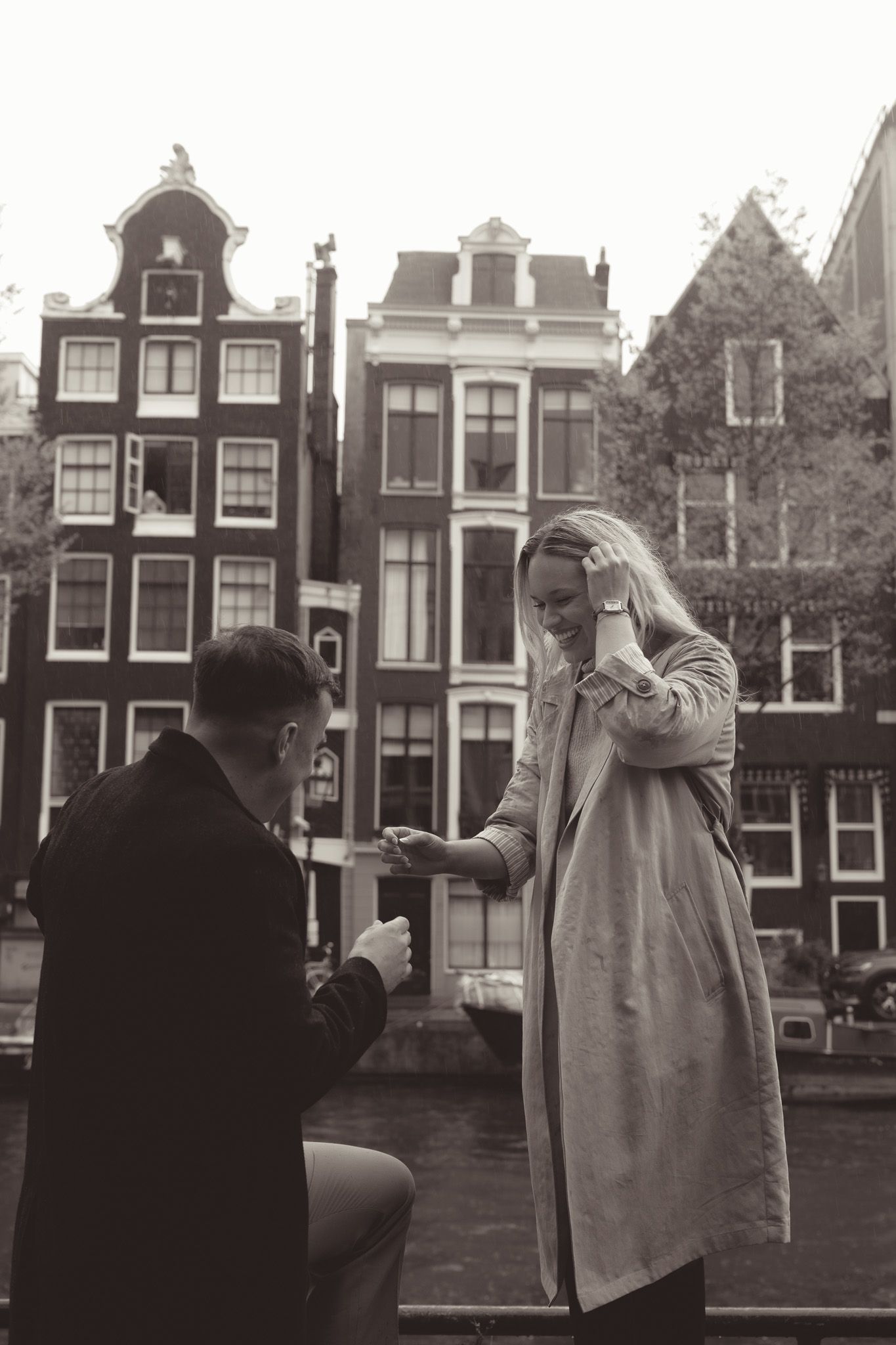 Proposal scene in Amsterdam with traditional Dutch canal houses in background.