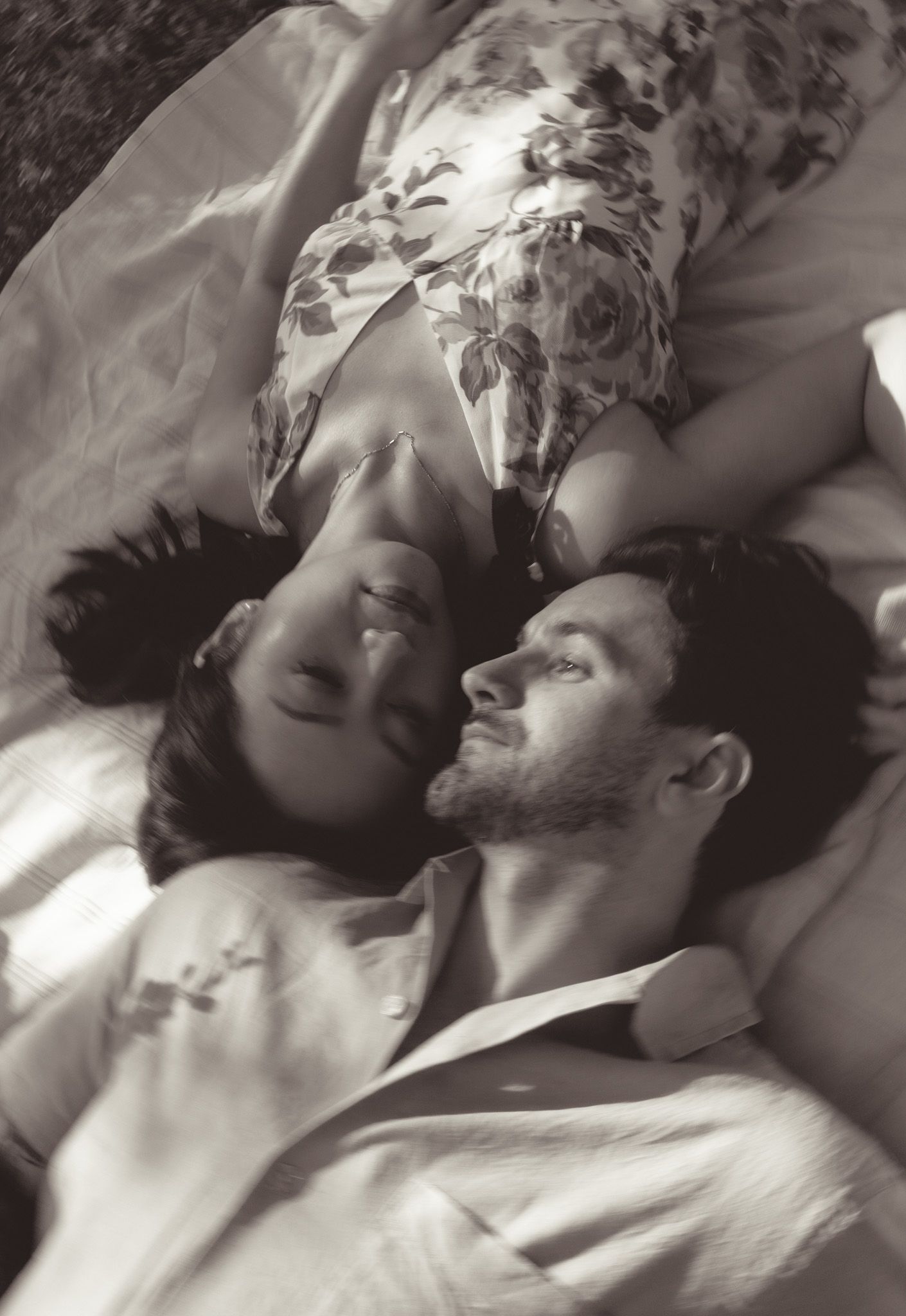 Intimate black and white portrait of couple resting on floral pillowcase.