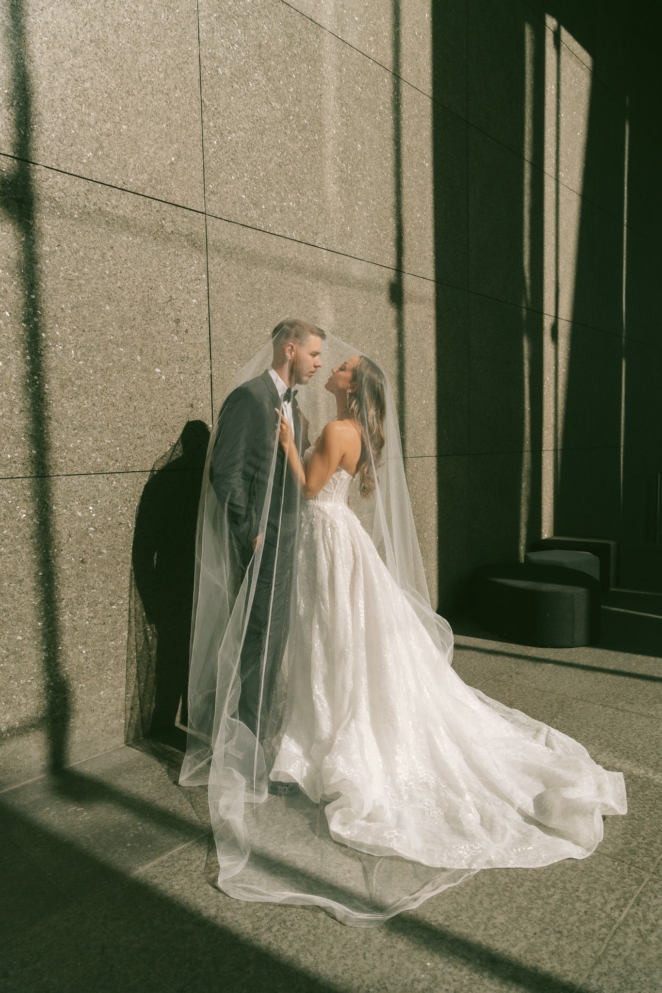 A series of four photos showing a bride in a flowing white gown with a long veil against a stone wall in dramatic lighting.