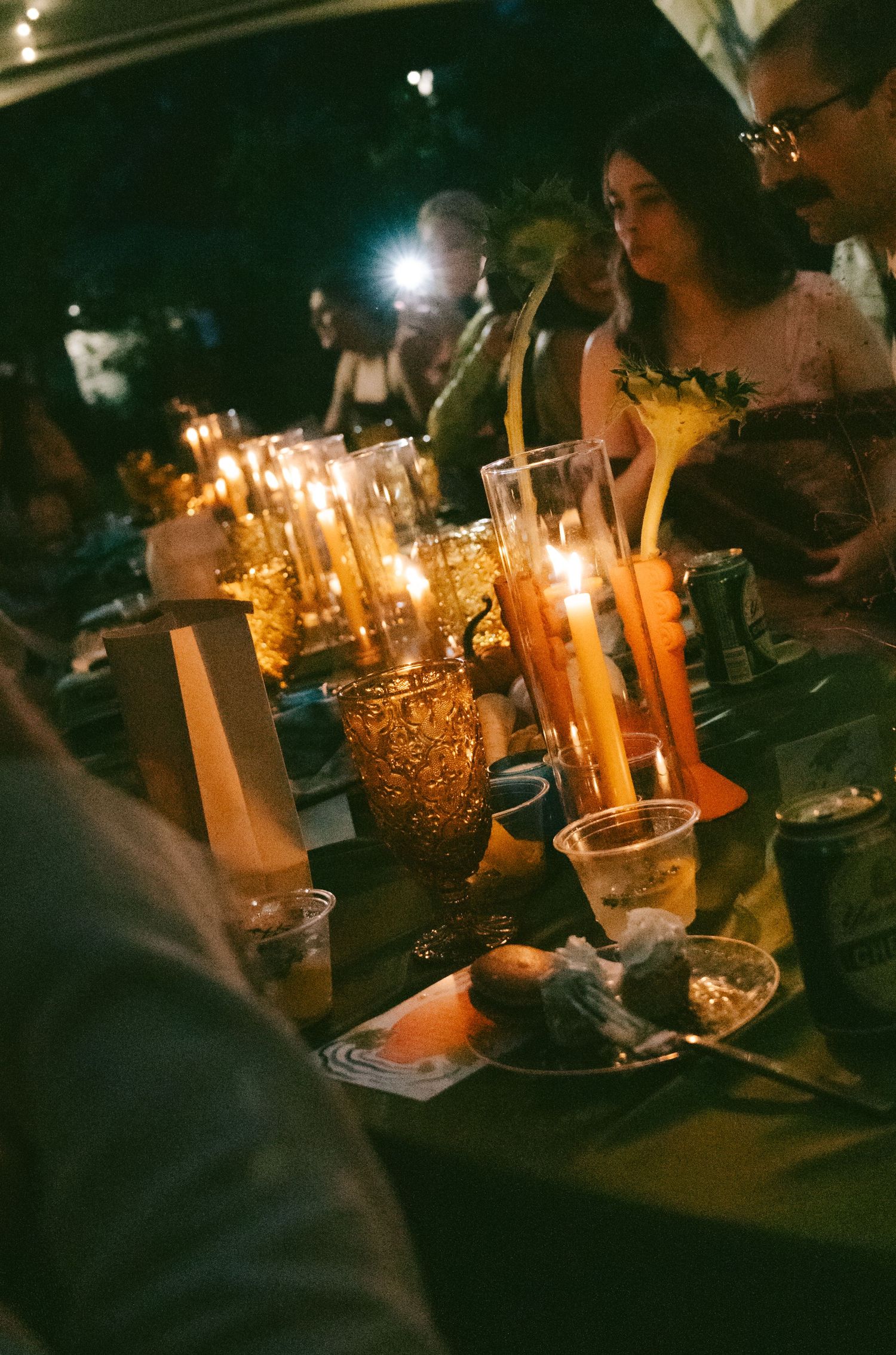 Glowing candles illuminate a dark room during a nighttime gathering, creating a warm and intimate ambiance.