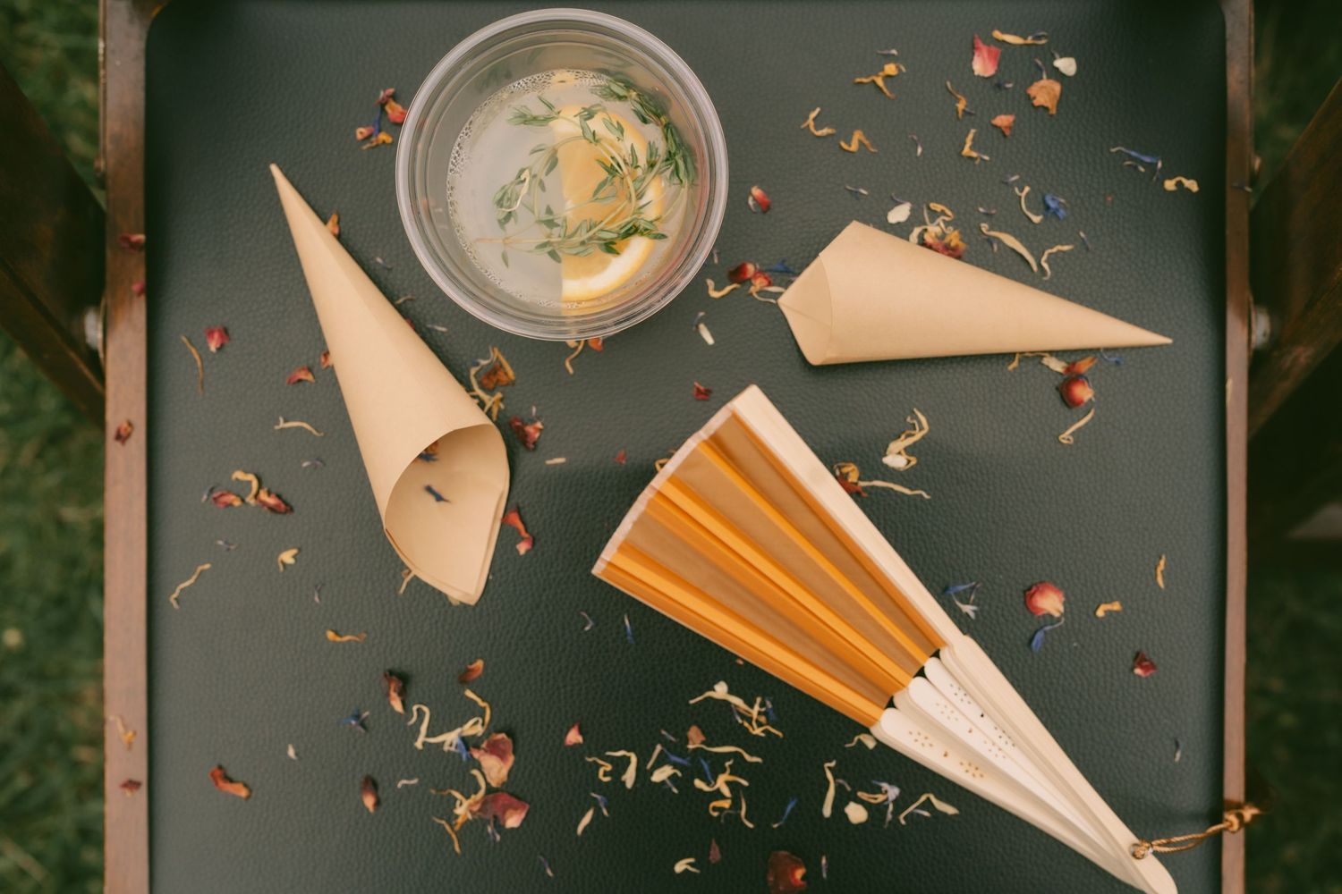 Artistic overhead shot of empty plates and scattered flower petals on a dark surface.