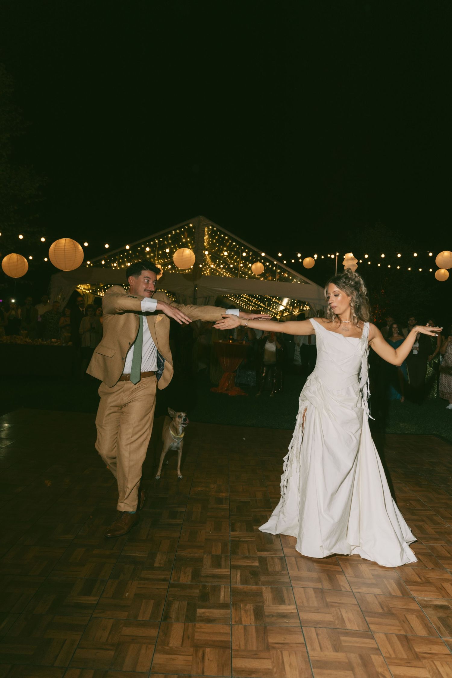 Wedding reception dance floor with string lights and paper lanterns creating a magical evening atmosphere.