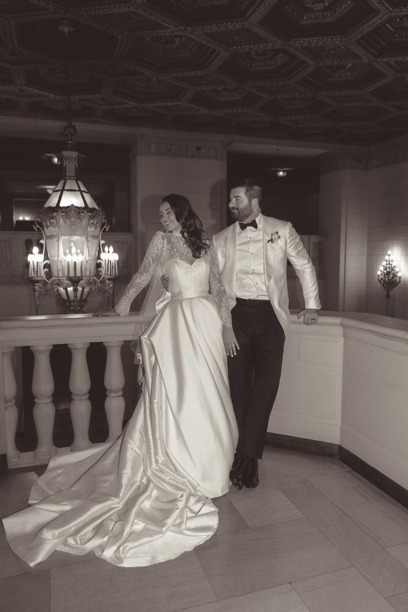 Classic flash black and white photo of a couple in wedding attire by an ornate balustrade under chandelier lighting in downtown pittsburgh,