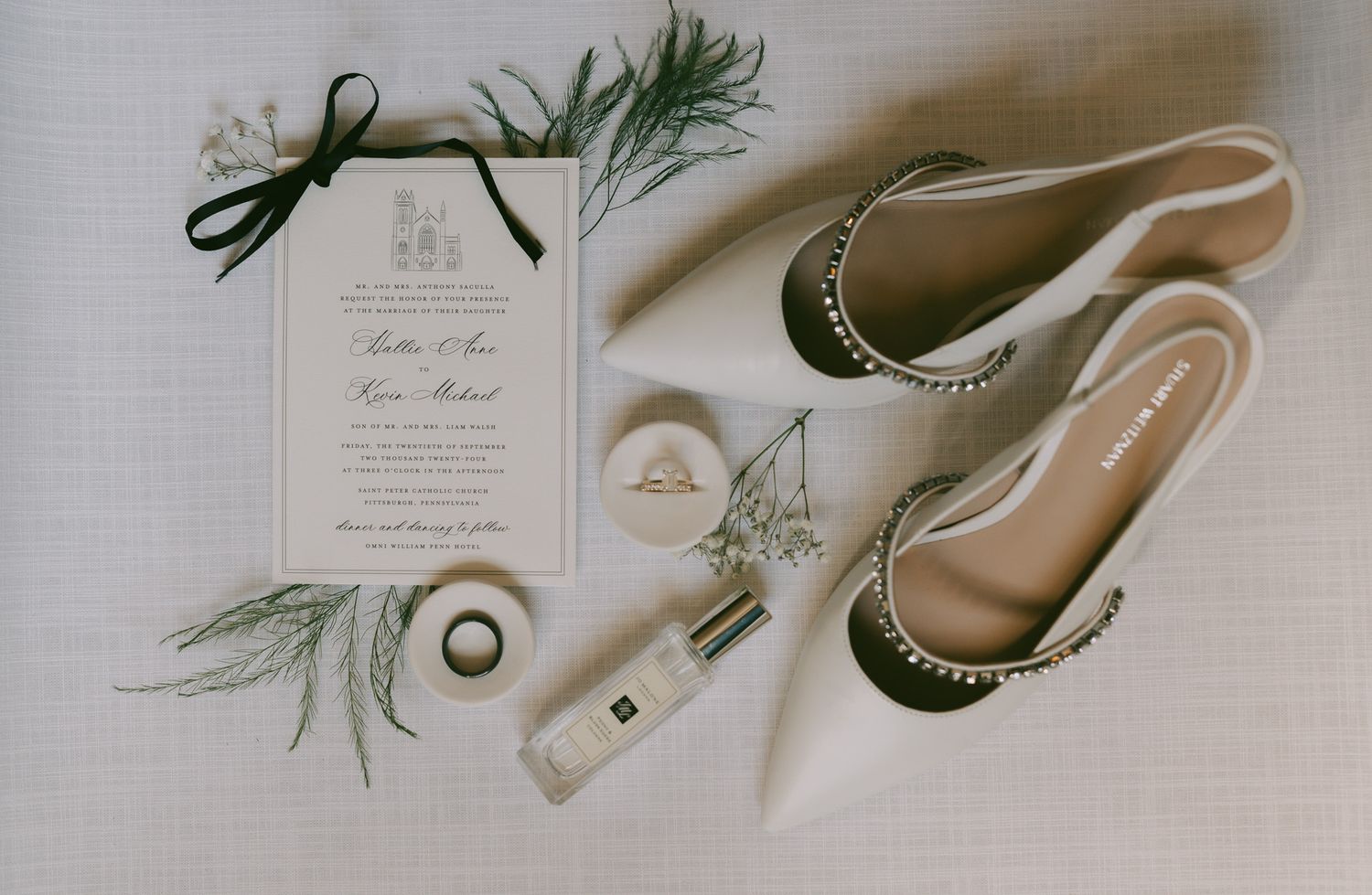 Wedding invitation with green sprigs and elegant bridal flats arranged on white surface in downtown pittsburgh, pa..