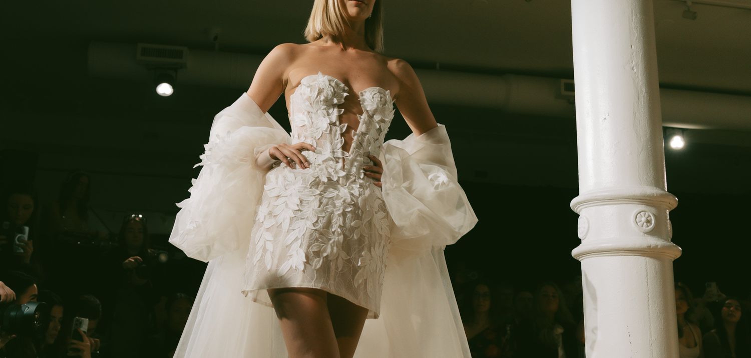 A fashion model wearing an elegant Berta strapless mini dress with floral appliques and dramatic tulle overskirt in SoHo, NYC.