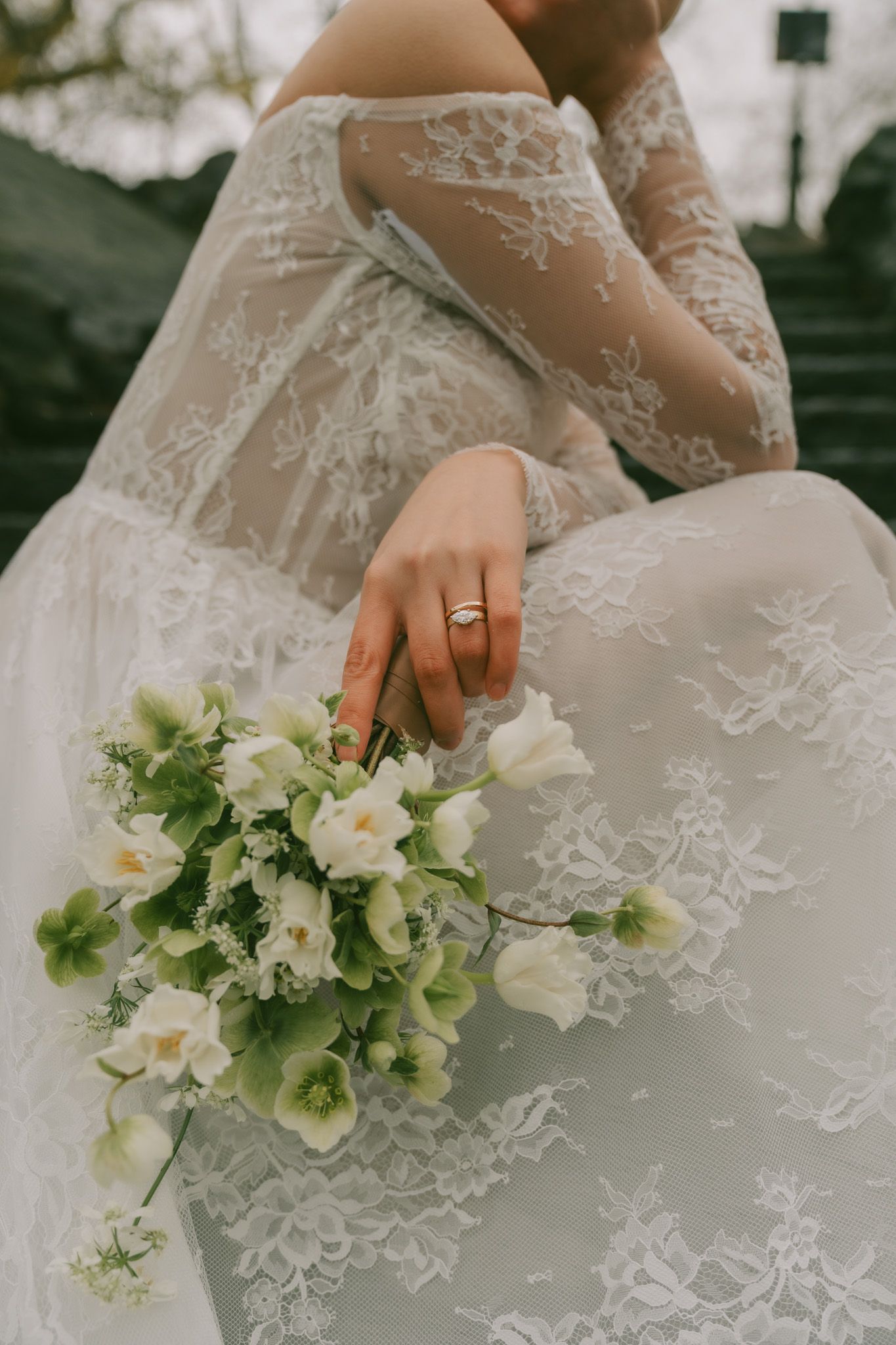 Detail shot of white lace House of Flora wedding dress with delicate floral bouquet in NYC.