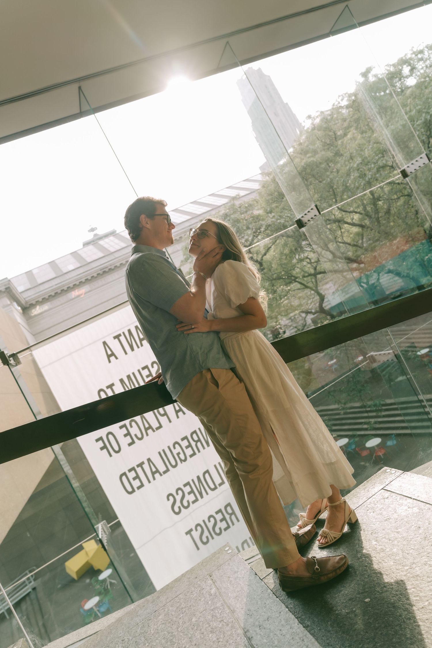 A couple sharing an intimate moment in front of a storefront window.
