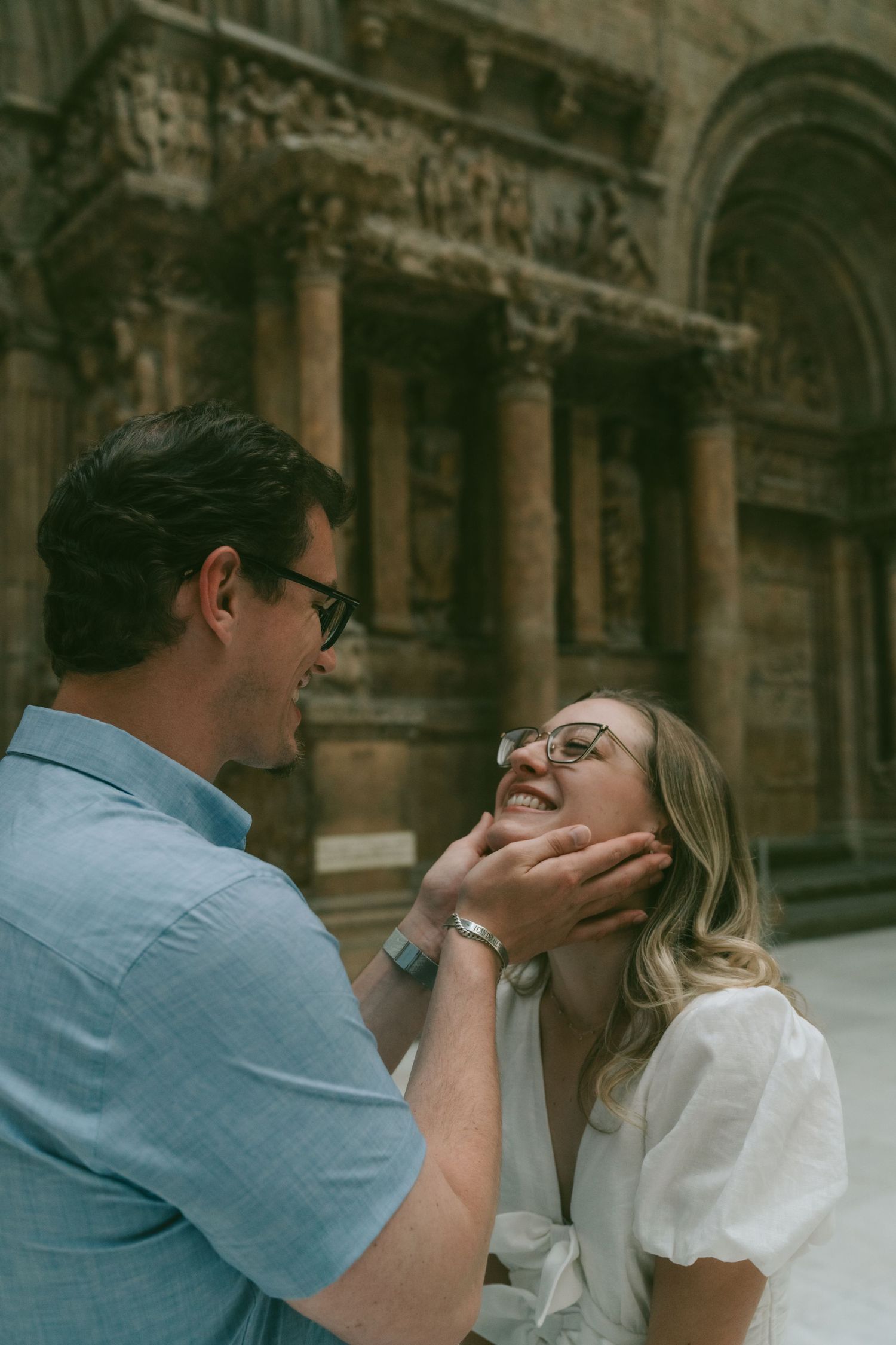 A couple sharing a romantic moment together against a historic stone building backdrop.