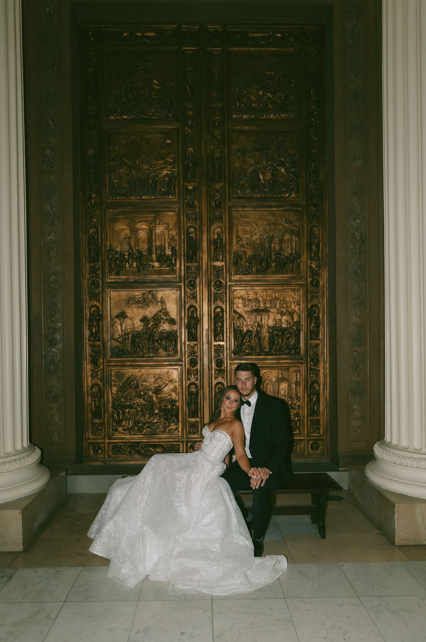 Newlywed couple poses against ornate wooden panels in elegant wedding portraits.