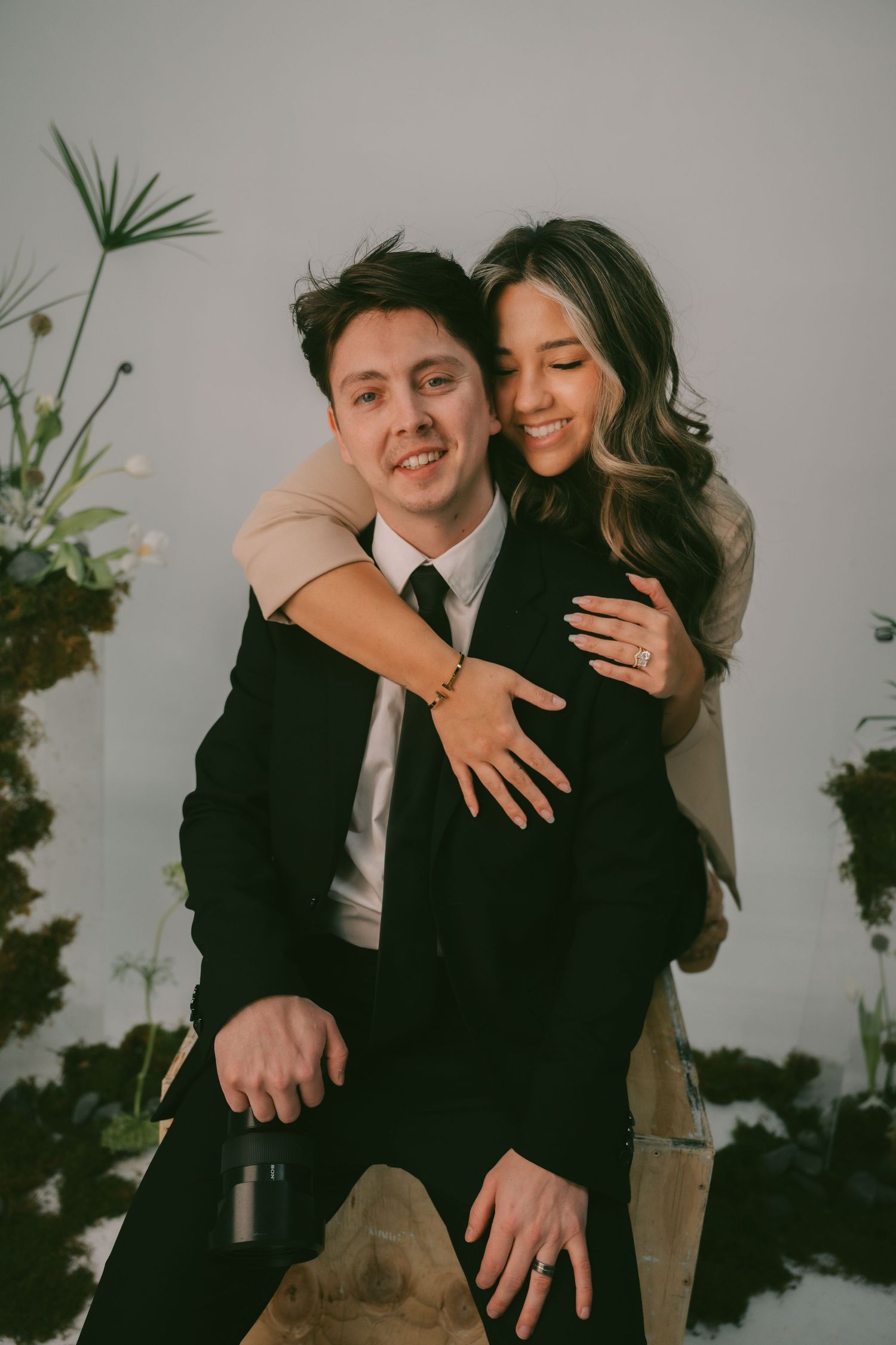 A couple embraces intimately in a series of romantic black and white engagement photos against a neutral background.