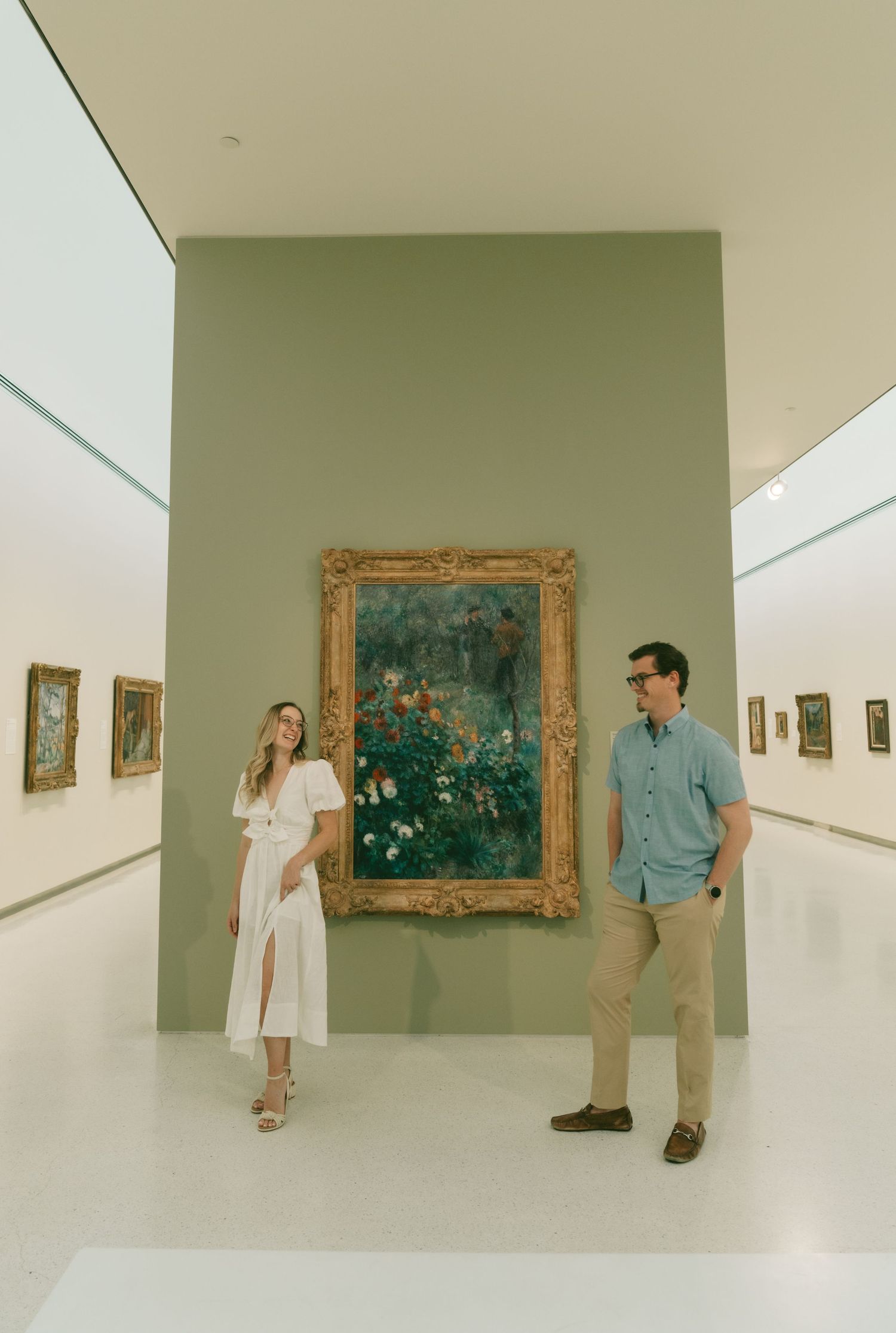 Art gallery interior with white walls displaying framed paintings.