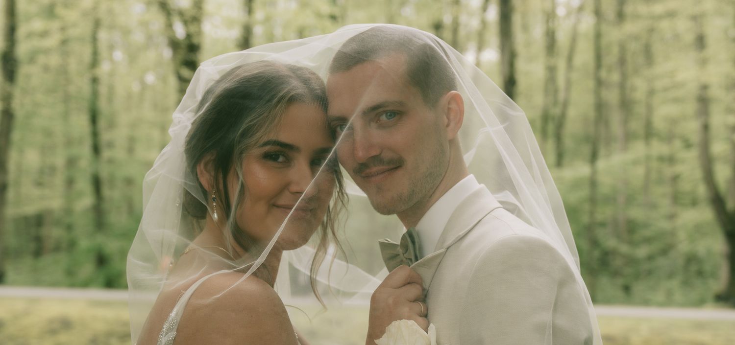 A romantic woodland wedding photo with soft natural lighting filtering through trees in Germany.