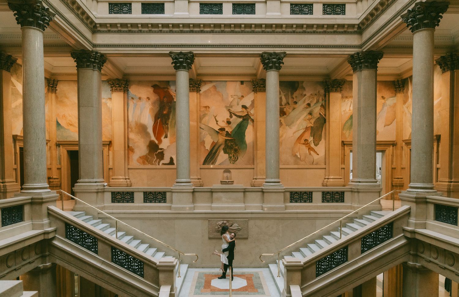 Classical art gallery with grand marble staircases, ornate pillars and illuminated wall murals in an elegant carnegie museum of art