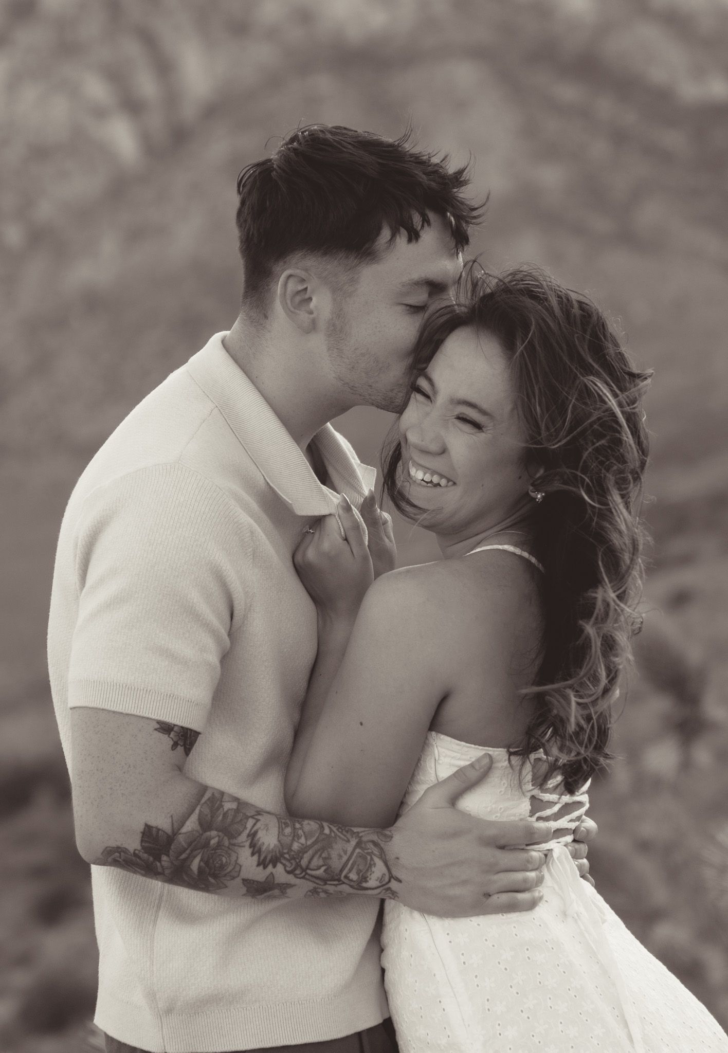 A romantic black and white portrait of a laughing couple embracing outdoors in intimate candid moment in red rock canyon, las vgeas.