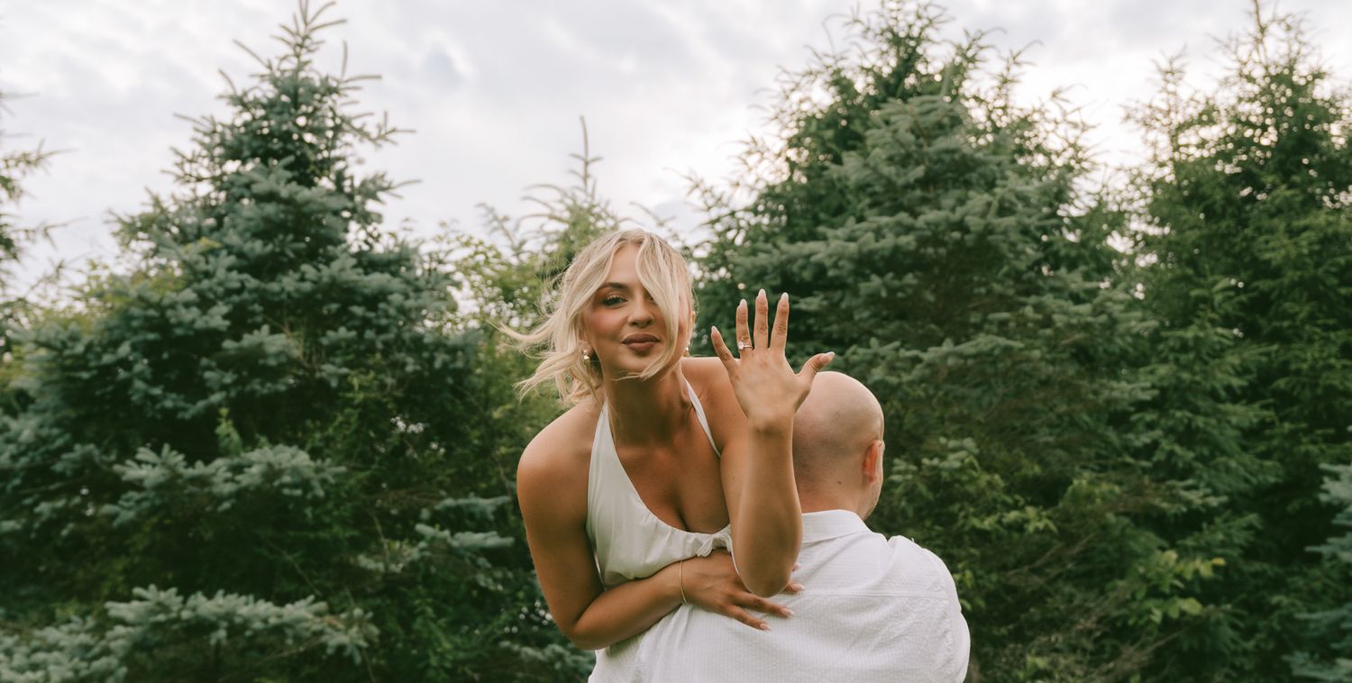 A joyful moment captured between two people outdoors with evergreen trees in the background.
