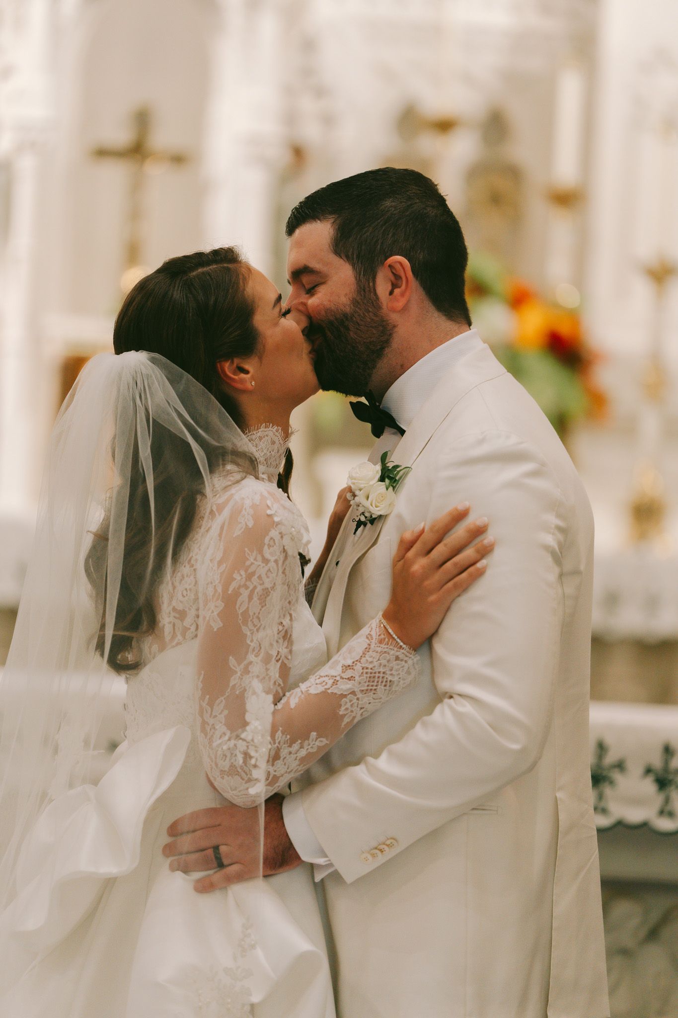 Romantic wedding moment in white church interior with cross visible in background in downtown pittsburgh, pa.