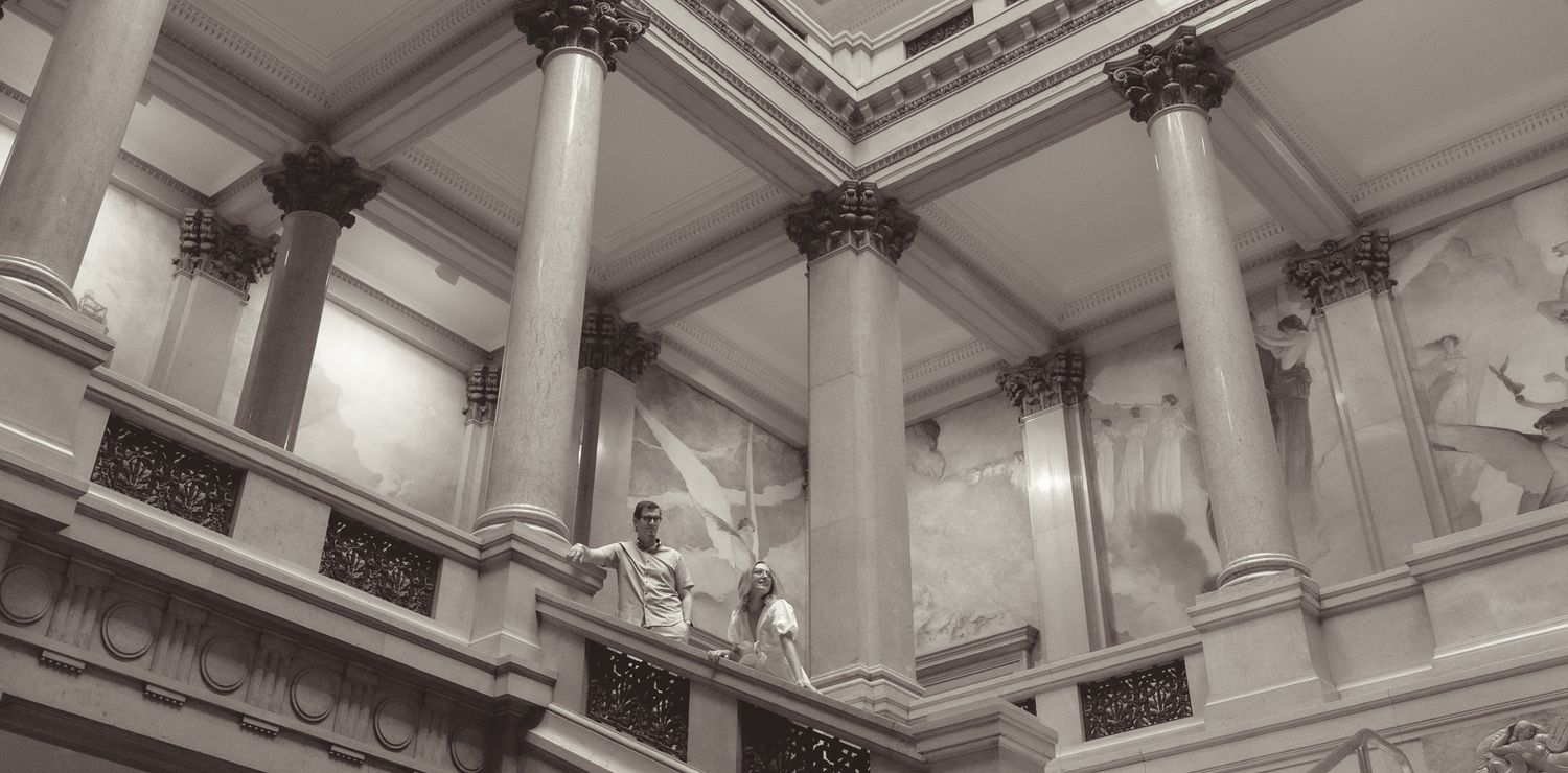 Ornate architectural detail of classical columns and marble staircase in historic interior space.
