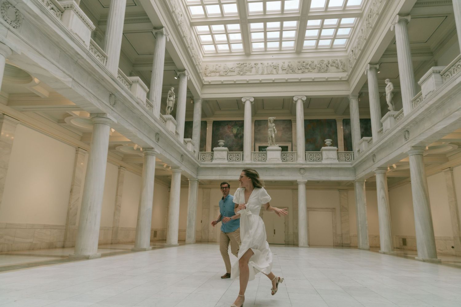 Interior shots of a grand hall with classical columns and skylight showing movement and dance.