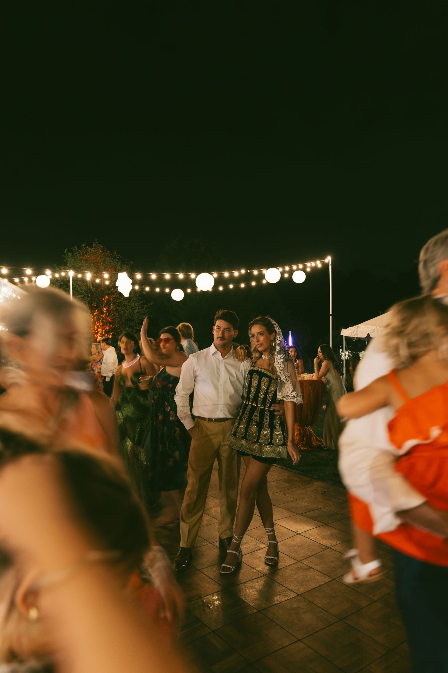 Evening wedding reception dance floor with string lights creating a romantic ambiance.