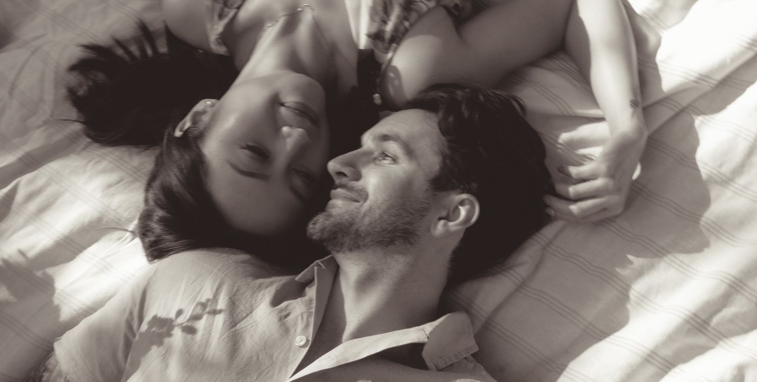 A black and white photograph showing a couple laying together intimately on white blanket in shenley park, pittsburgh..