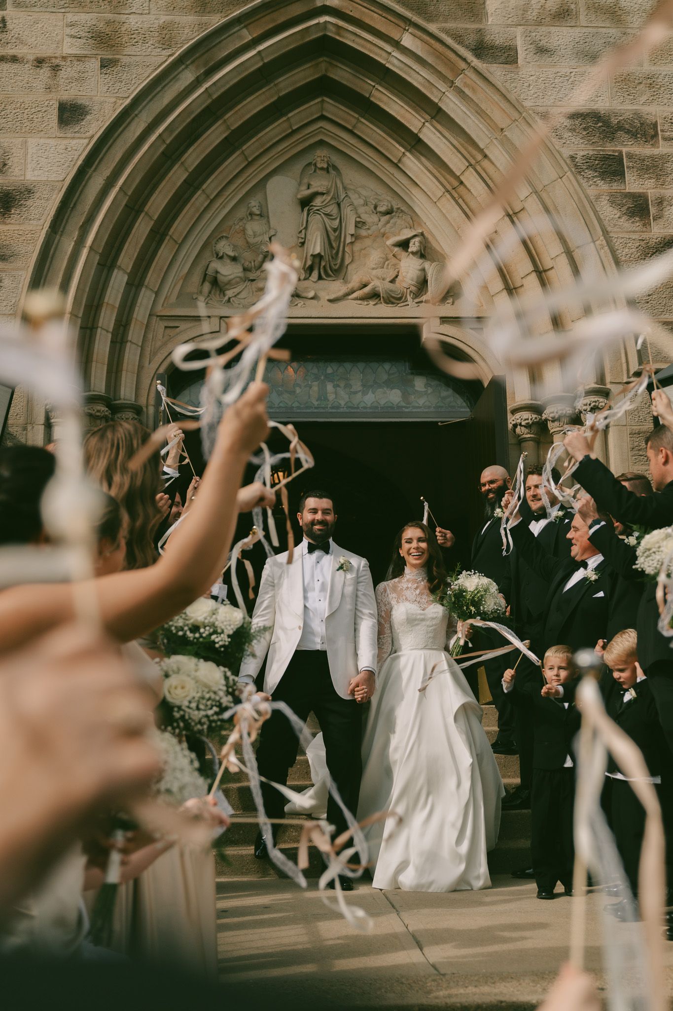 Wedding couple exits church while guests wave ribbons in celebration in downtown pittsburgh, pa.