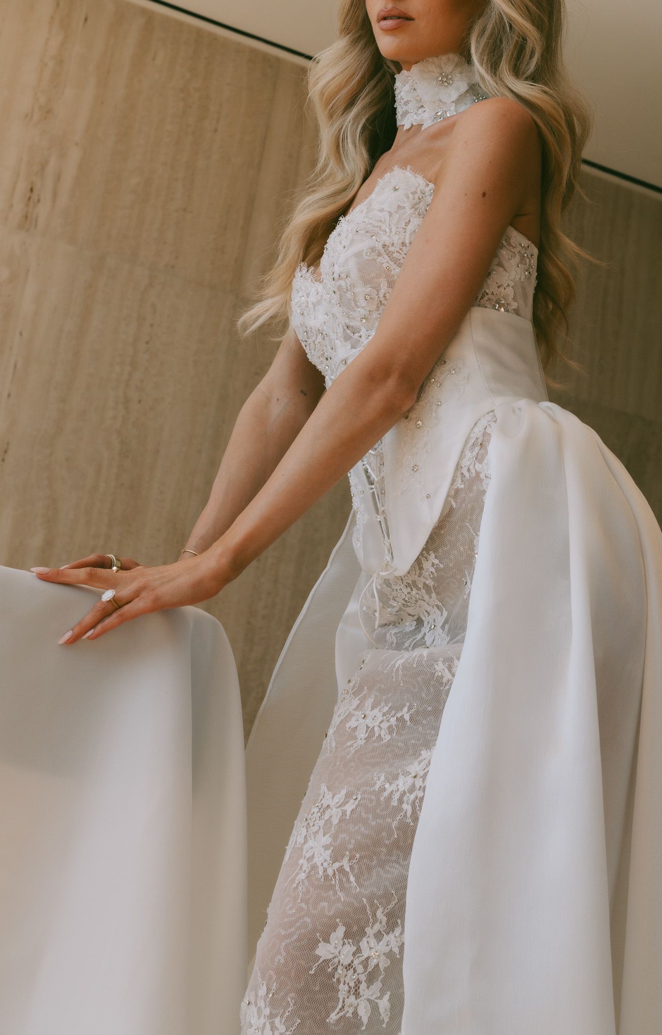White lace Eden Aharon wedding gown with structured overlay detail shown in soft lighting.