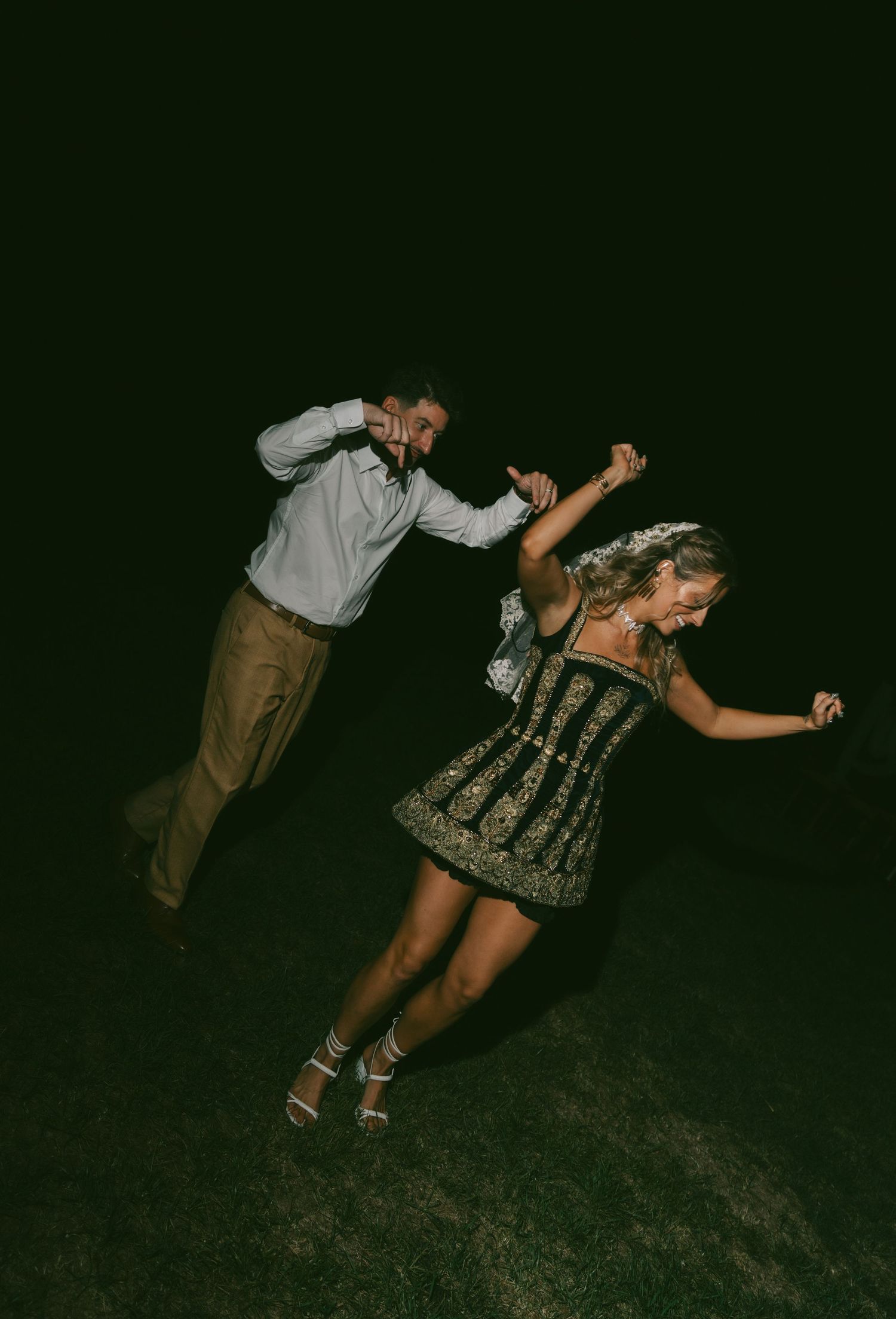 Dancers perform a theatrical dip pose outdoors at night in traditional German dress.