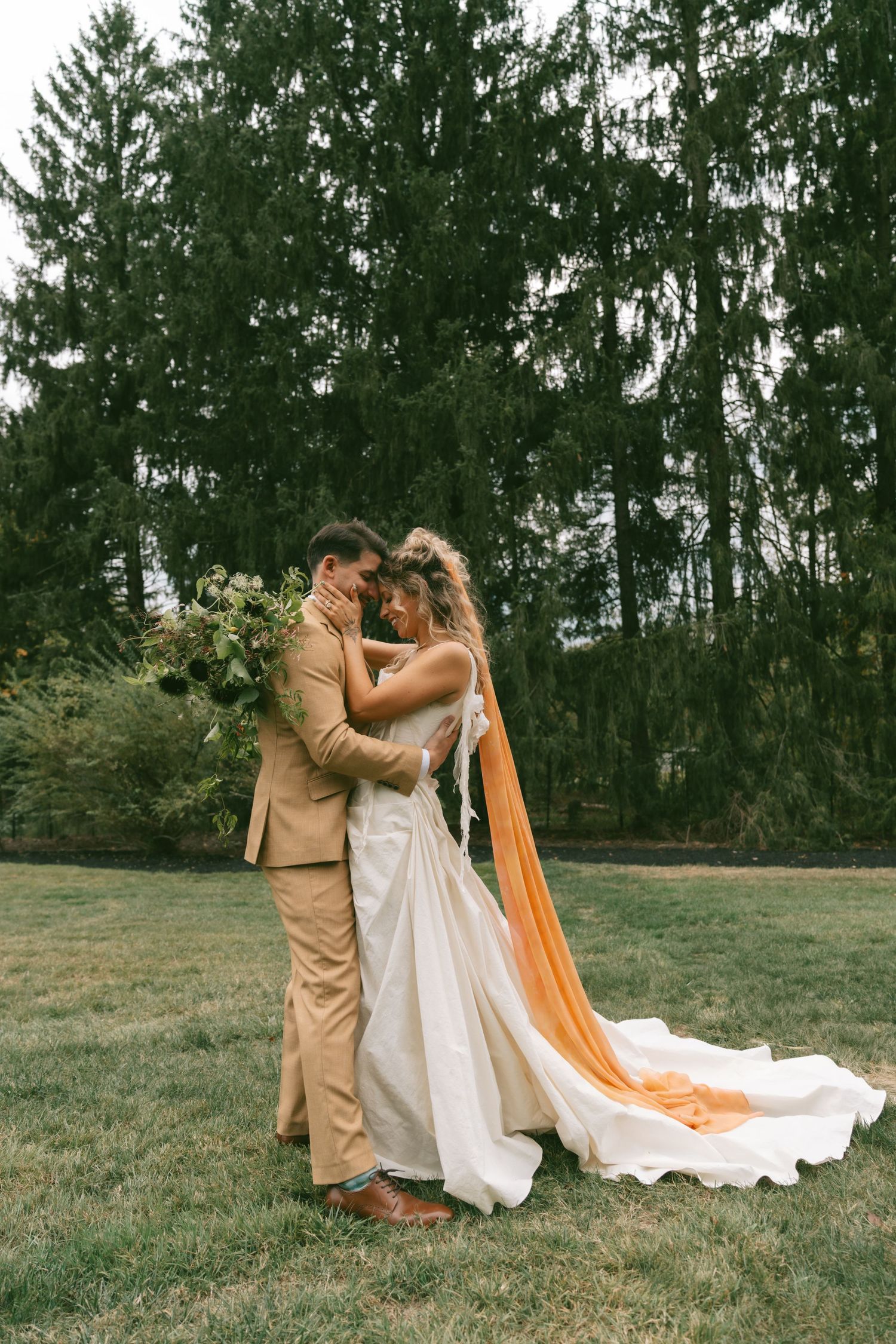 A romantic outdoor wedding moment captured against a backdrop of evergreen trees.