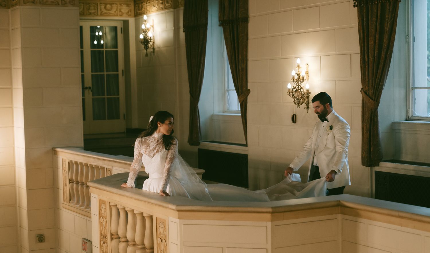 A panoramic view of a wedding couple and photographer during a photoshoot in an elegant interior hallway.