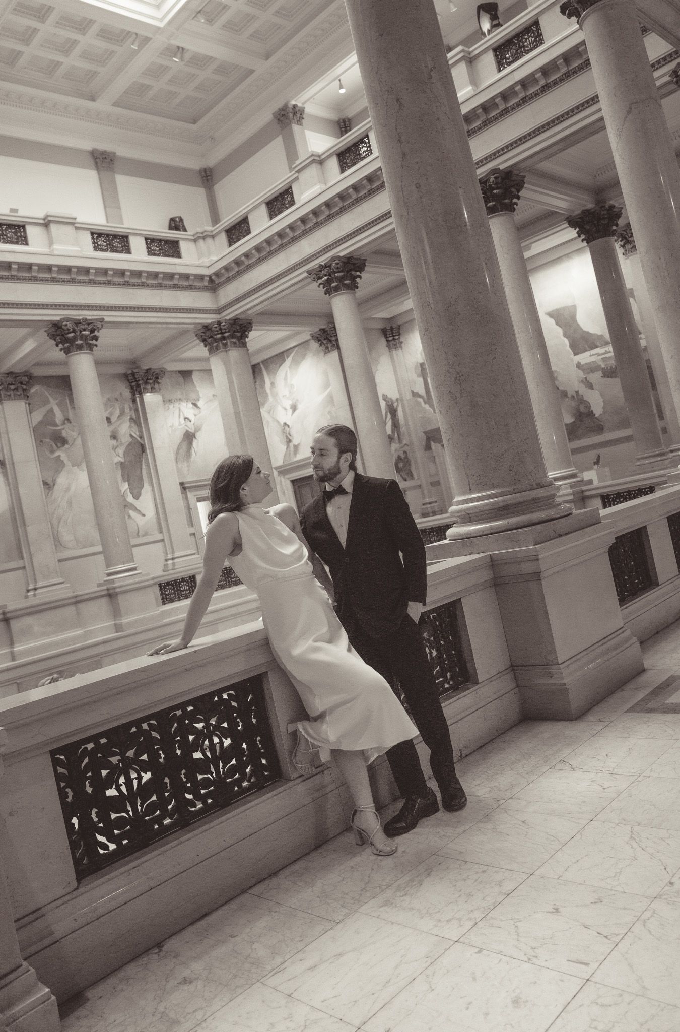 Black and white sequence shows movement along an ornate marble balcony.