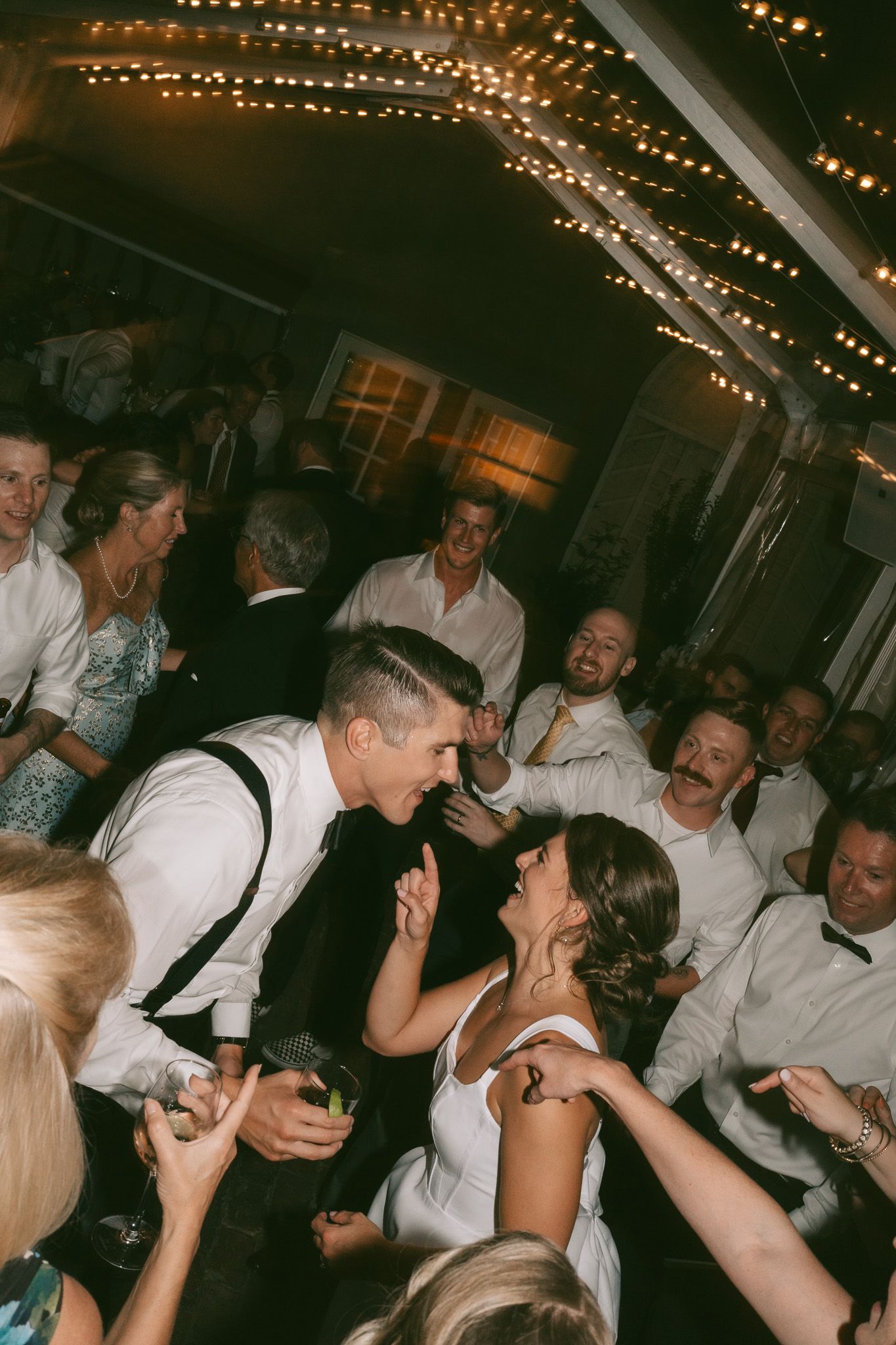 A series of candid party photos showing people dancing and celebrating at a dimly lit event with string lights overhead.