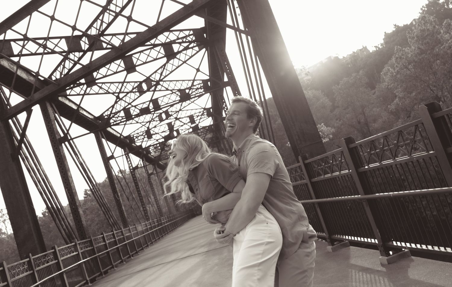 Black and white panoramic view of people walking across a steel bridge structure.