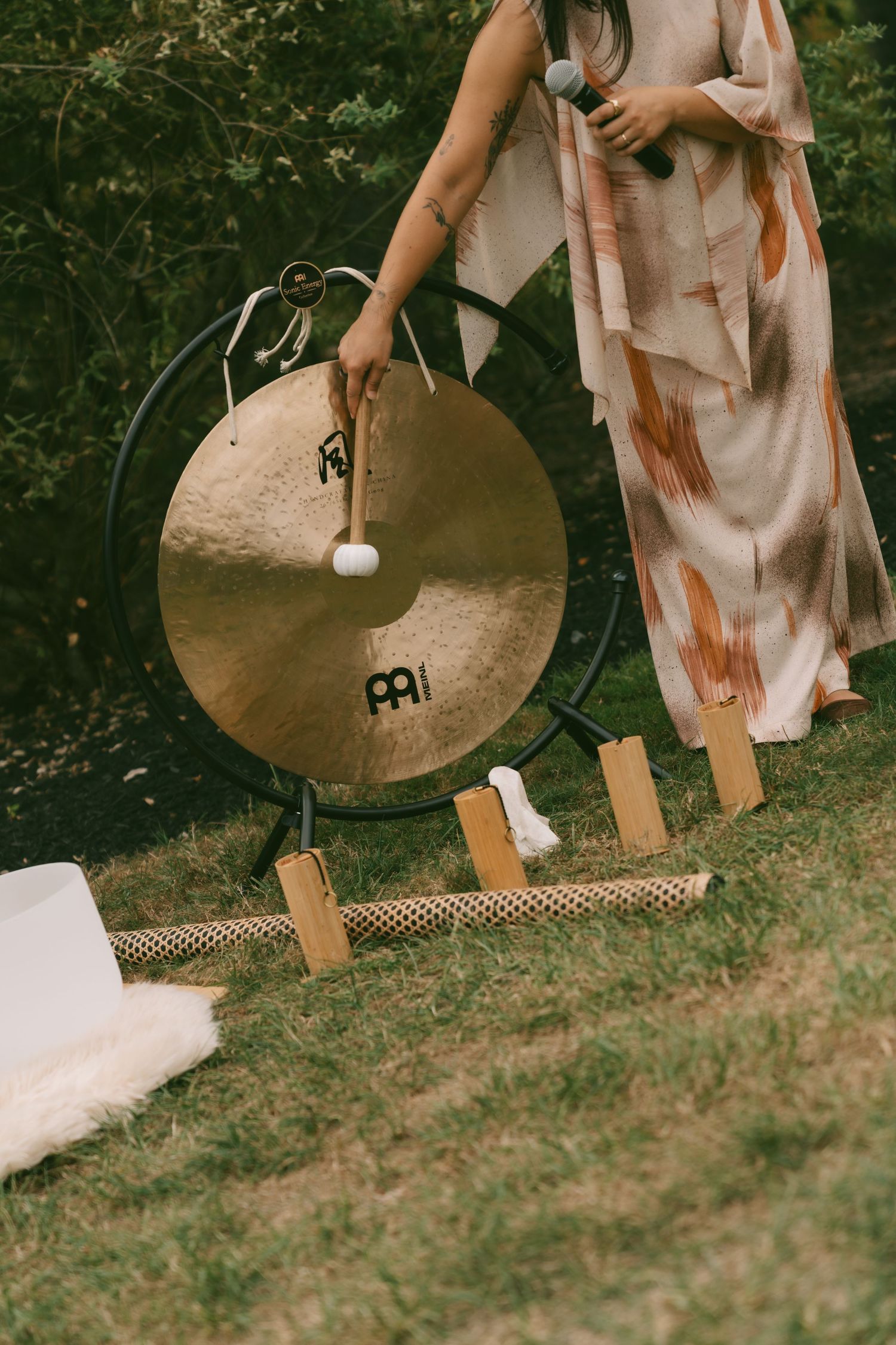 A close-up view of a cymbal and percussion equipment on grass outdoors.