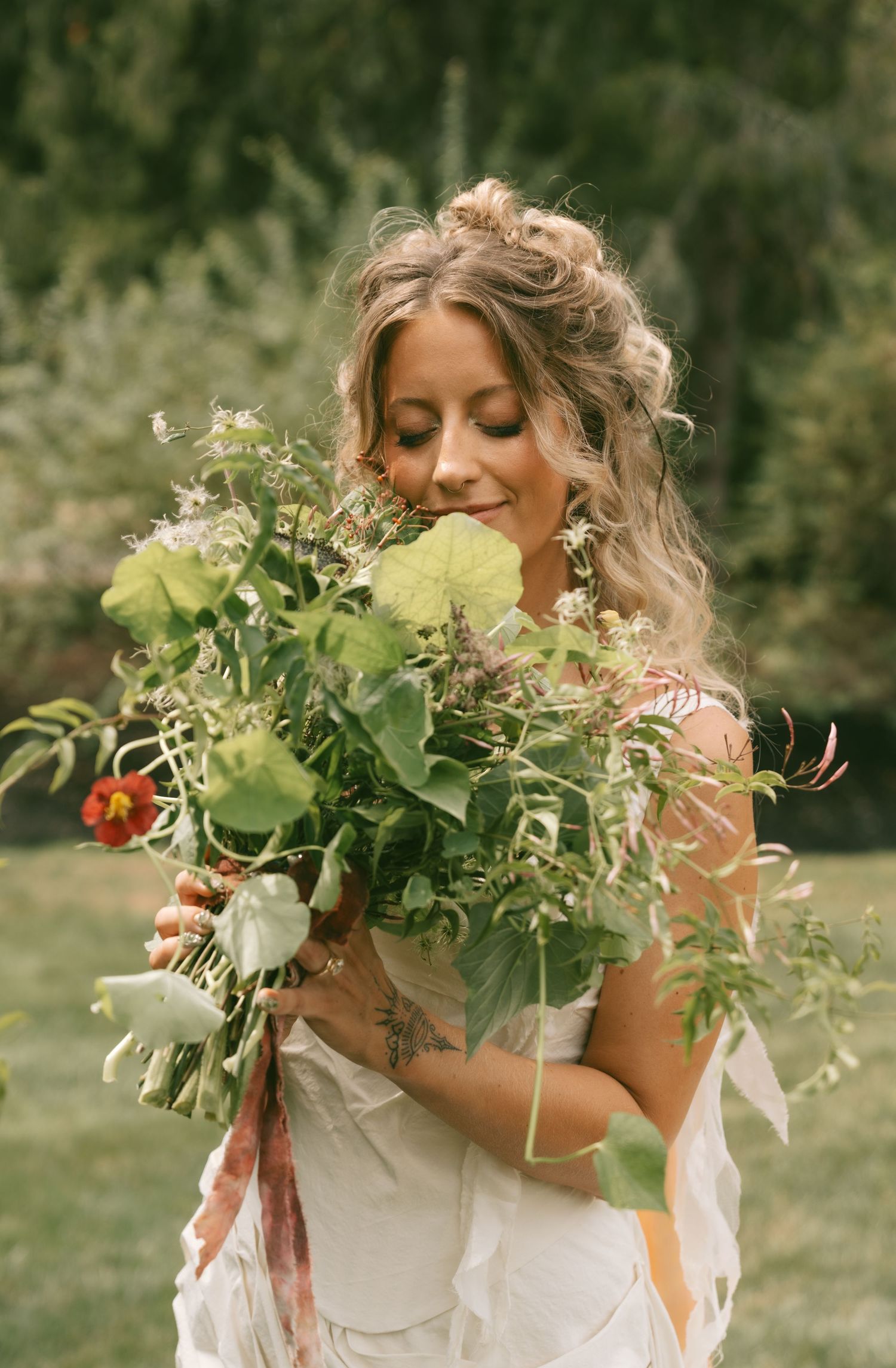 A white wedding dress and floral bouquet against a natural outdoor garden setting.