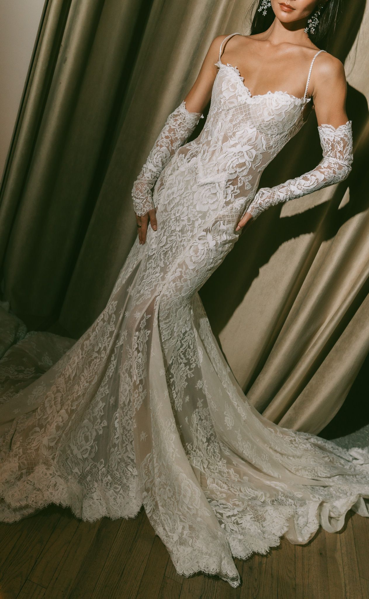 Elegant lace wedding dress with off-shoulder sleeves and flowing train shown from multiple angles on wooden floor.