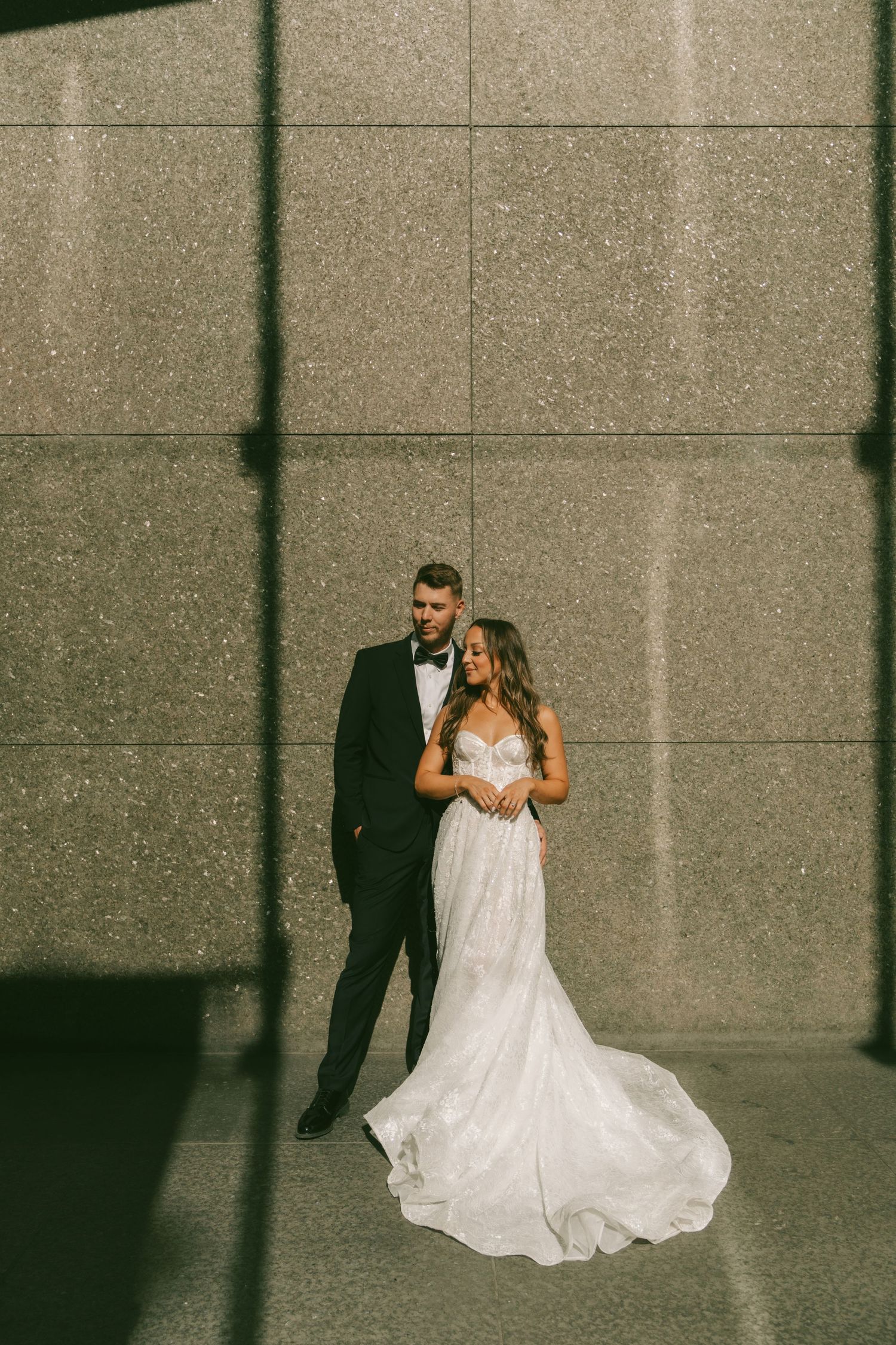 A newlywed couple dances and twirls together against an industrial backdrop with beautiful natural lighting.