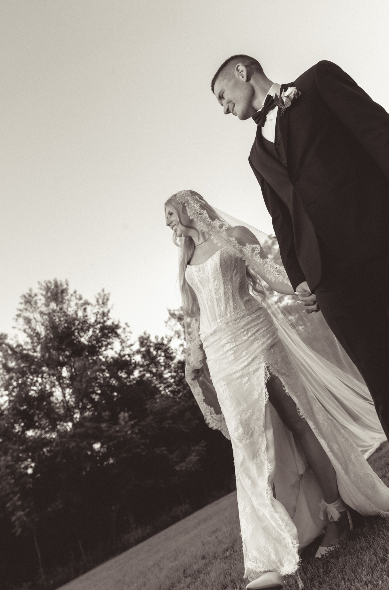 Black and white wedding photo sequence showing a bride in white dress walking with groom in suit on a hillside.