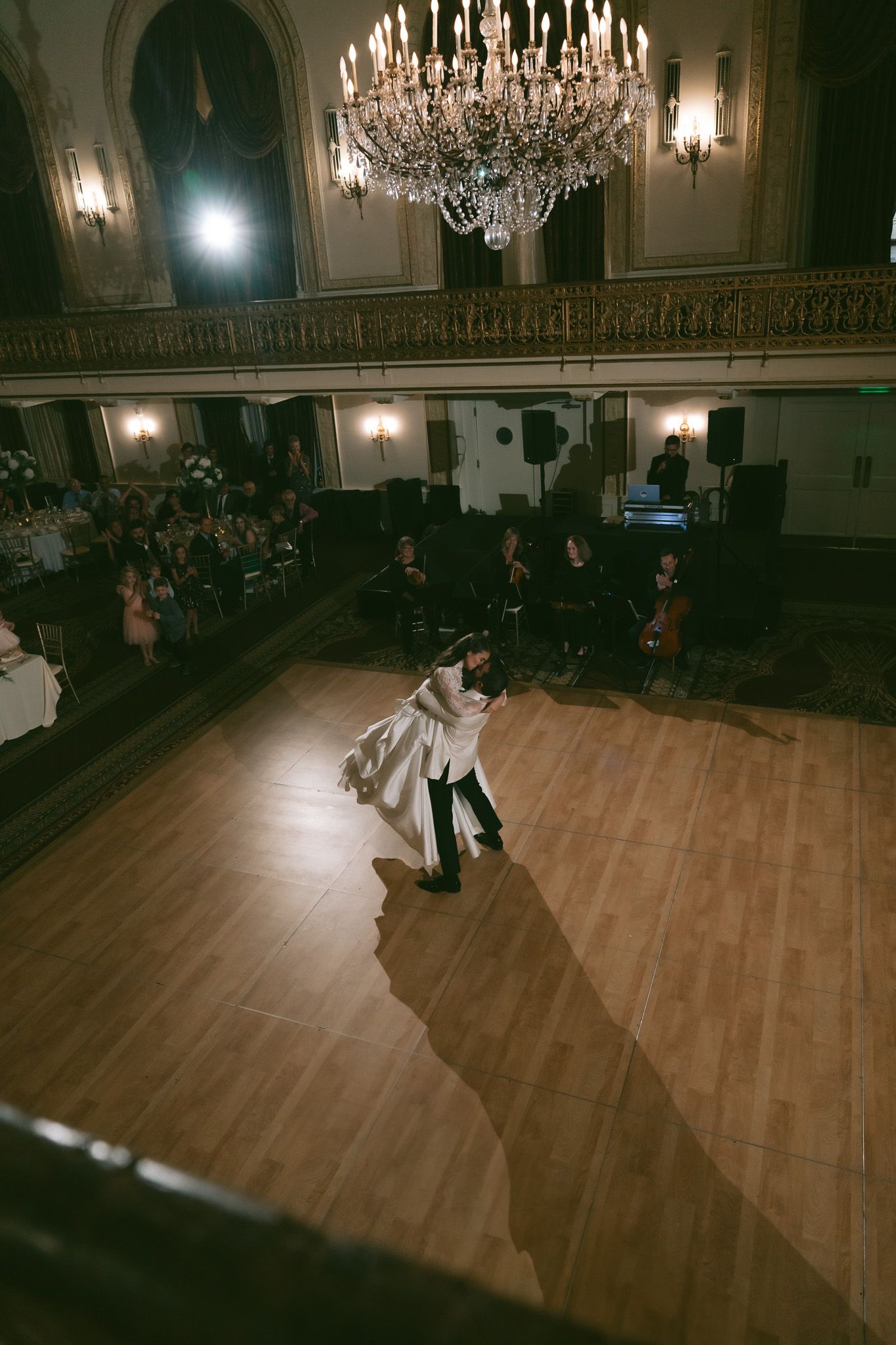 Couple dancing in an elegant ballroom with crystal chandelier and audience watching from tables in downtown pittsburgh, pa.