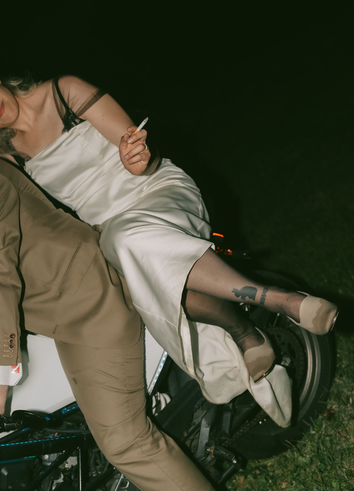 Nighttime motorcycle scene with white dress and tan suit in dramatic lighting in Philedaphlia, pa