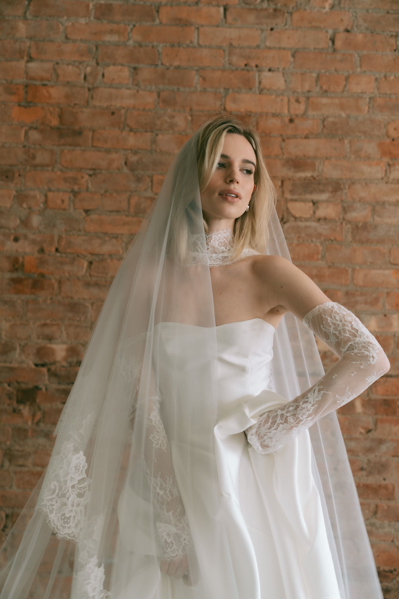 Ethereal bridal portrait featuring a House of Flora flowing tulle veil against exposed brick walls in New York City