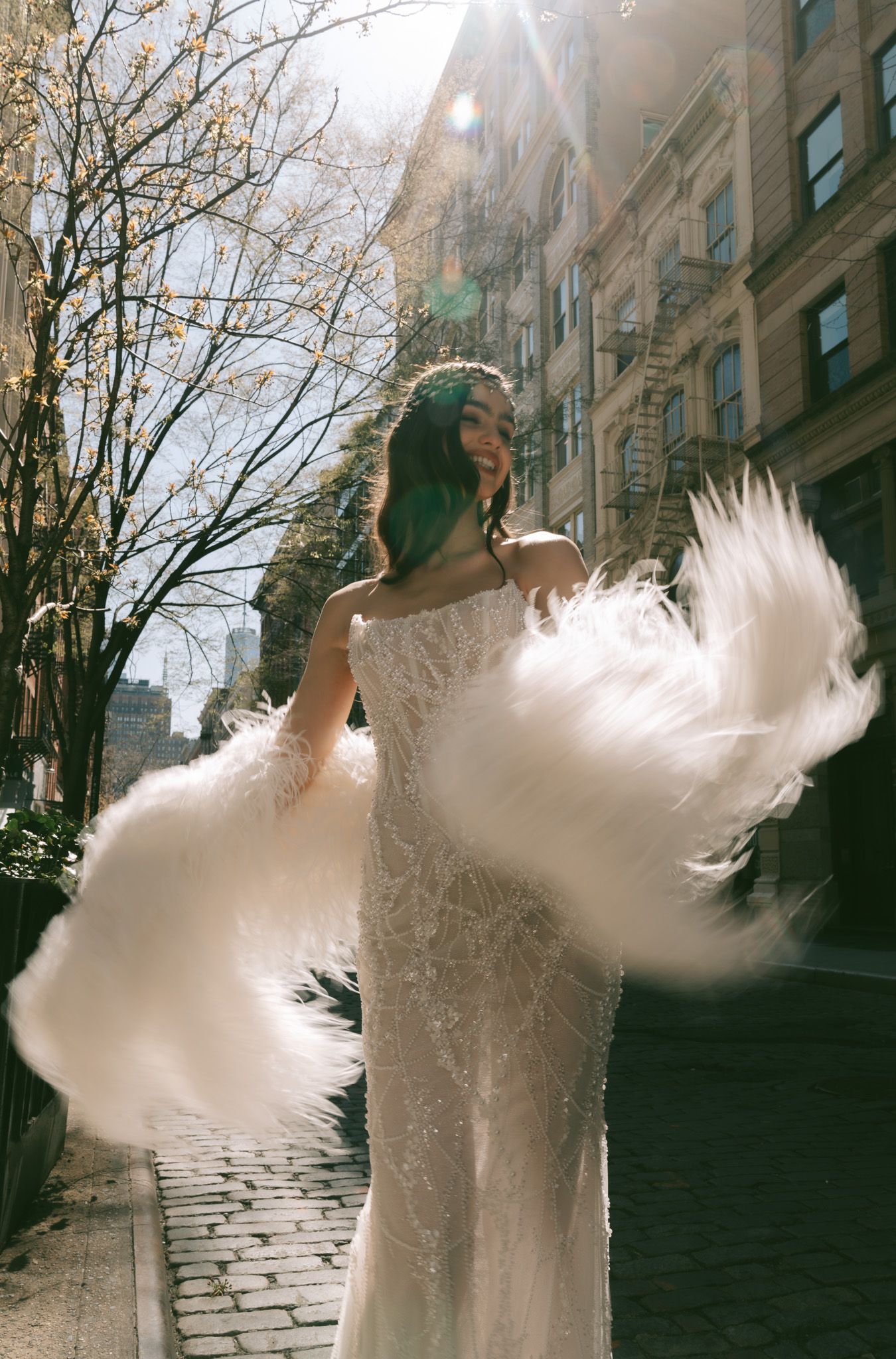 Ethereal Galia Lahav wedding dress captured in motion on city street with sunlight and trees.