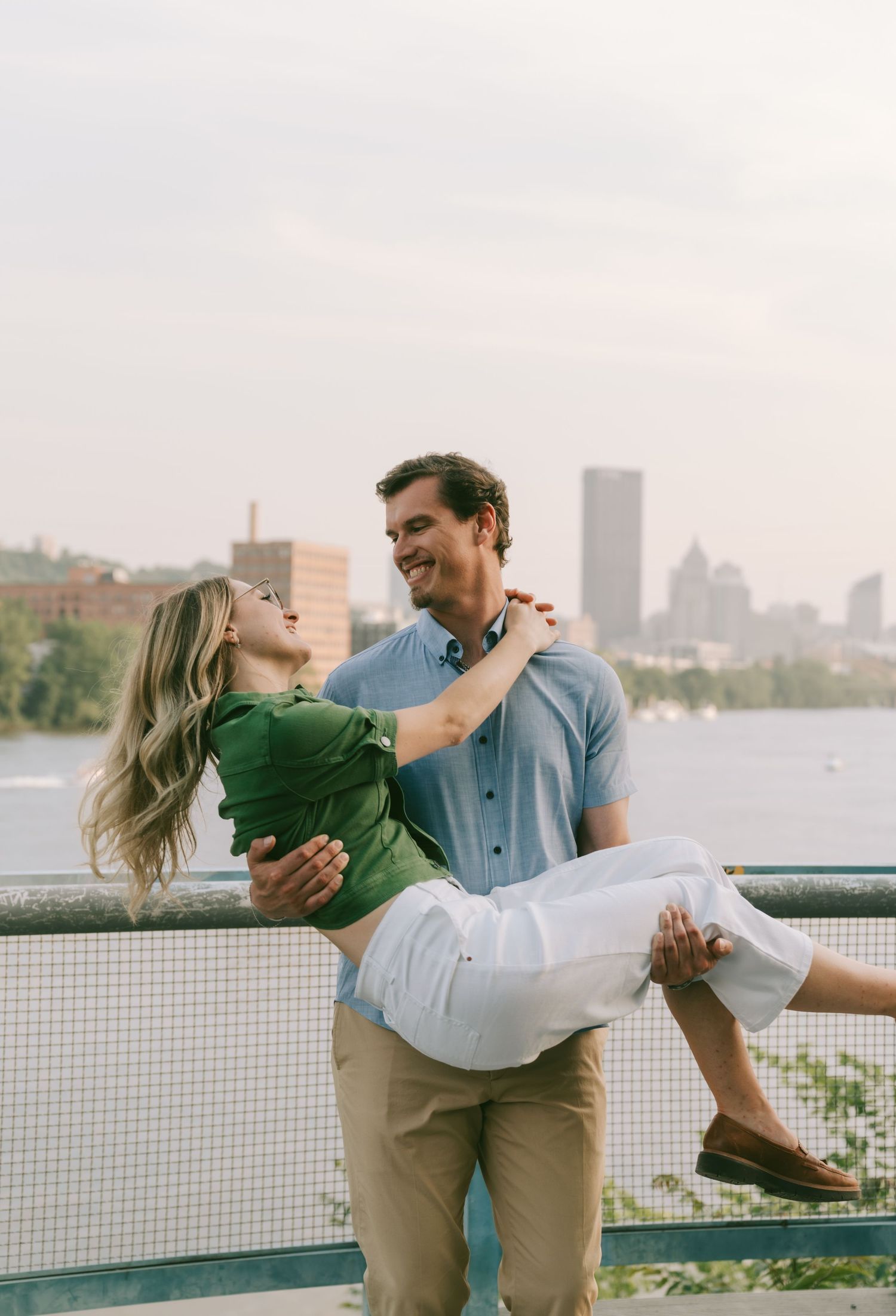 Romantic couple embracing on a rooftop terrace with city skyline in background.