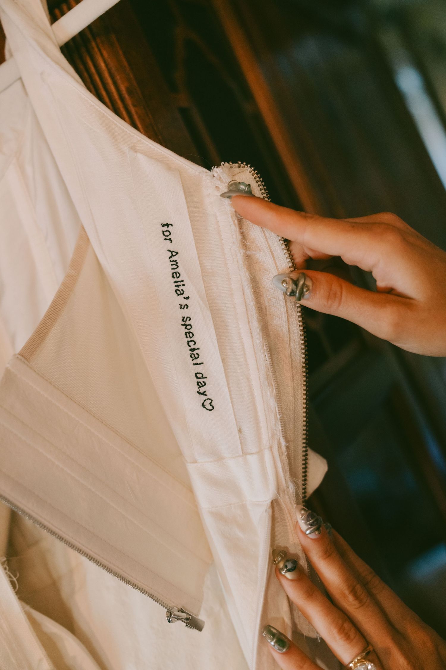 White garment bags with name tags being unzipped to reveal formal attire inside.