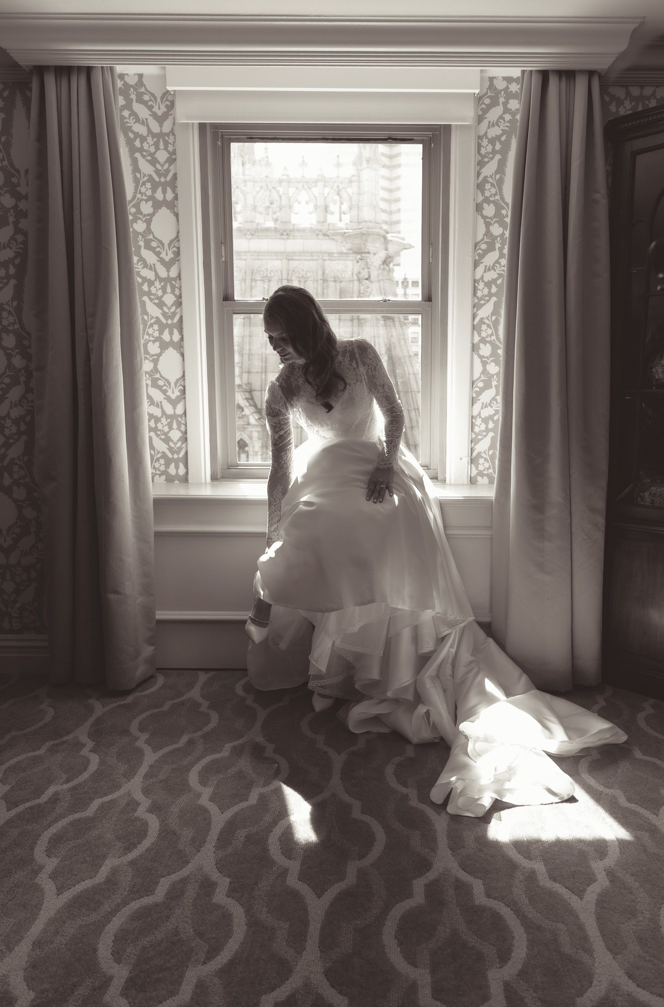 Artistic black and white photo of bride near window with patterned carpet and curtains in downtown pittsburgh, pa.
