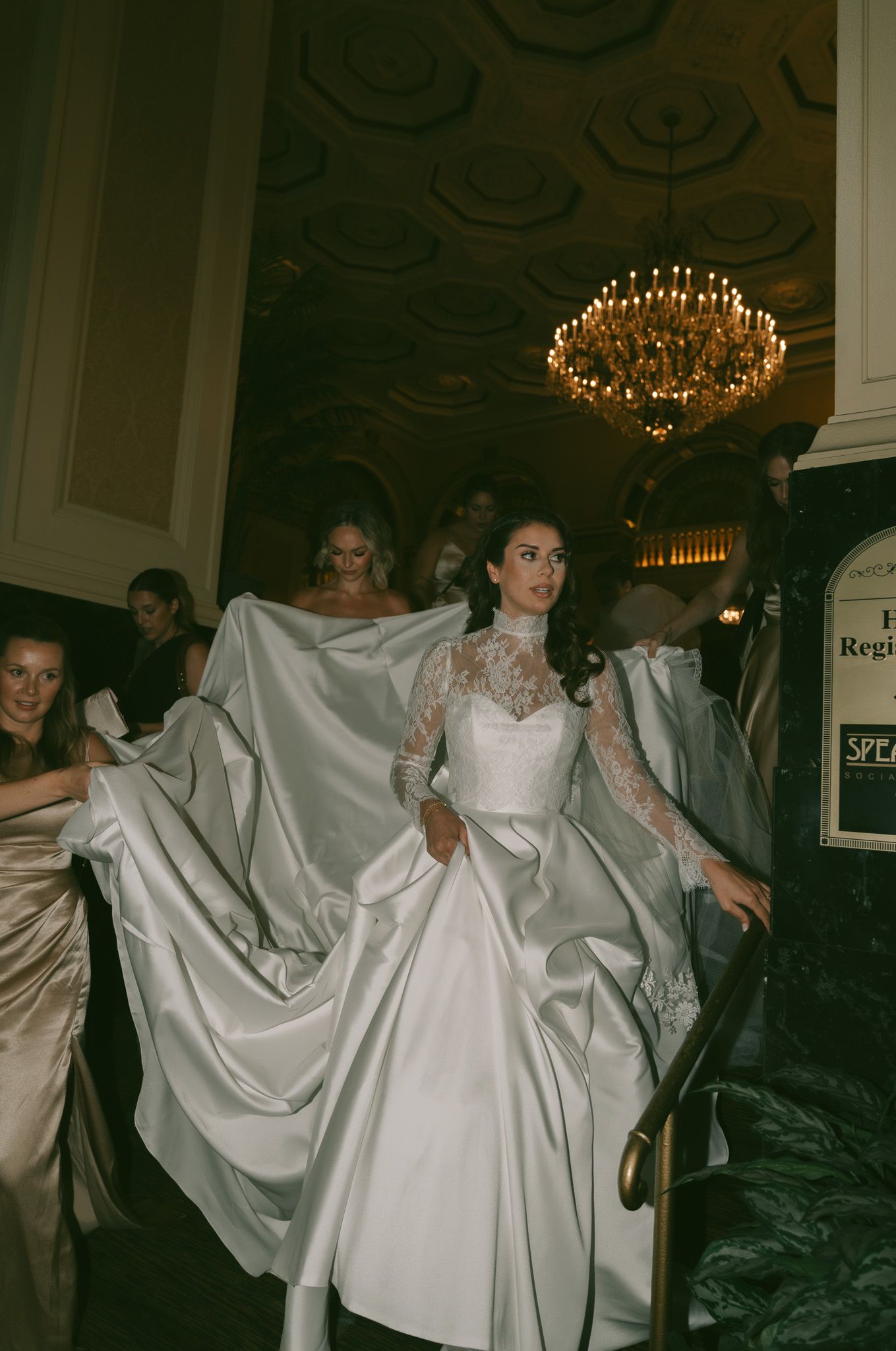 Wedding couple in an elegant ballroom performing a dramatic dance dip under chandeliers.