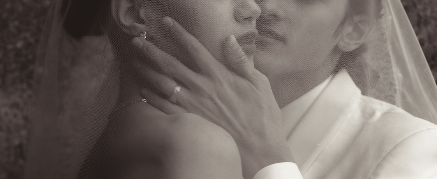 An intimate black and white close-up photograph capturing a tender moment between newlyweds.