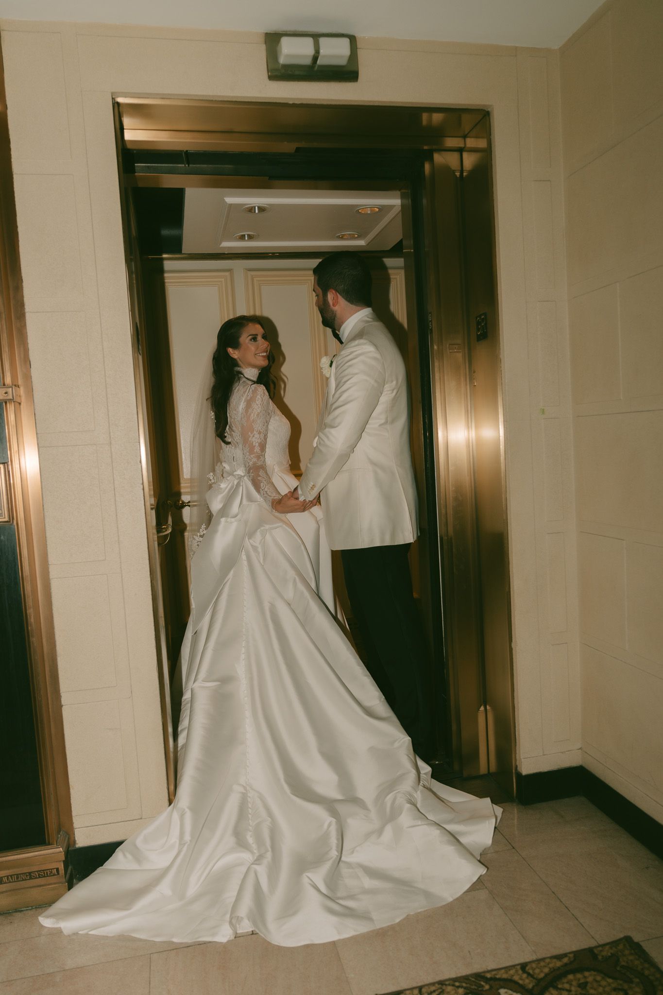 Elegant wedding photo in an elevator featuring a flowing white dress and formal attire in downtown pittsburgh, pa.