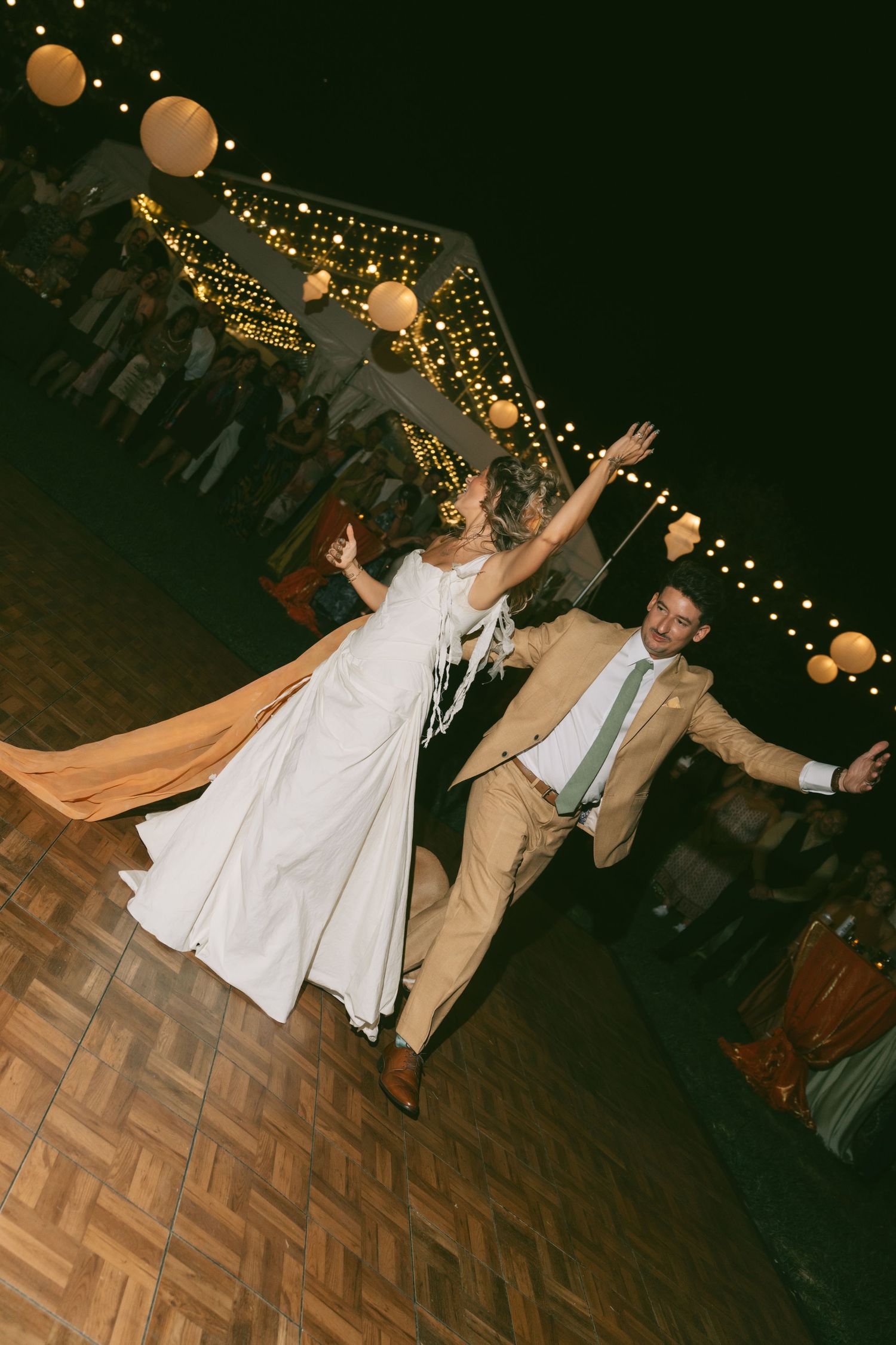 Wedding reception dance floor with string lights overhead and couples dancing.
