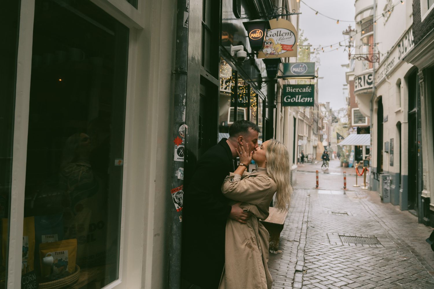 A couple shares an intimate moment on a charming cobblestone street in a European city.