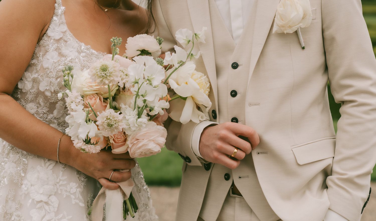 A bride and groom stand close together while holding elegant white floral bouquets at their wedding ceremony in Germany.